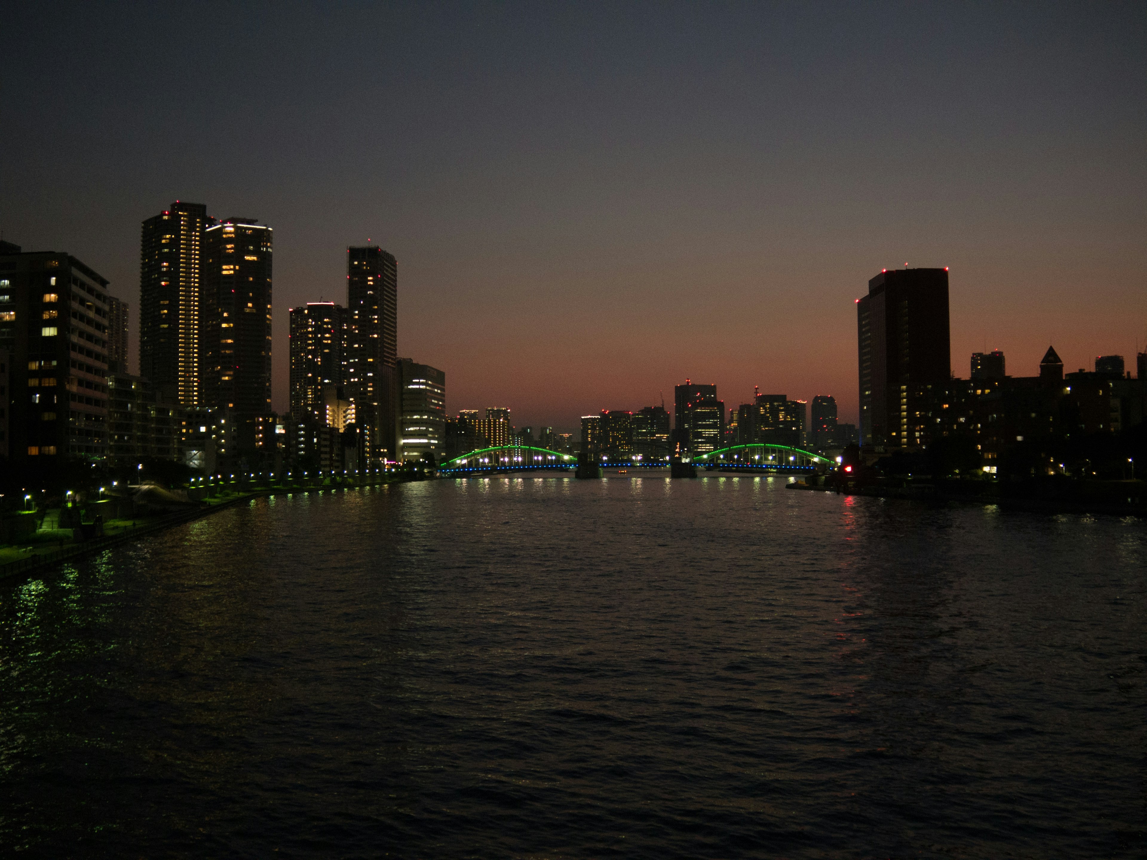 Horizonte urbano al anochecer con edificios iluminados y río