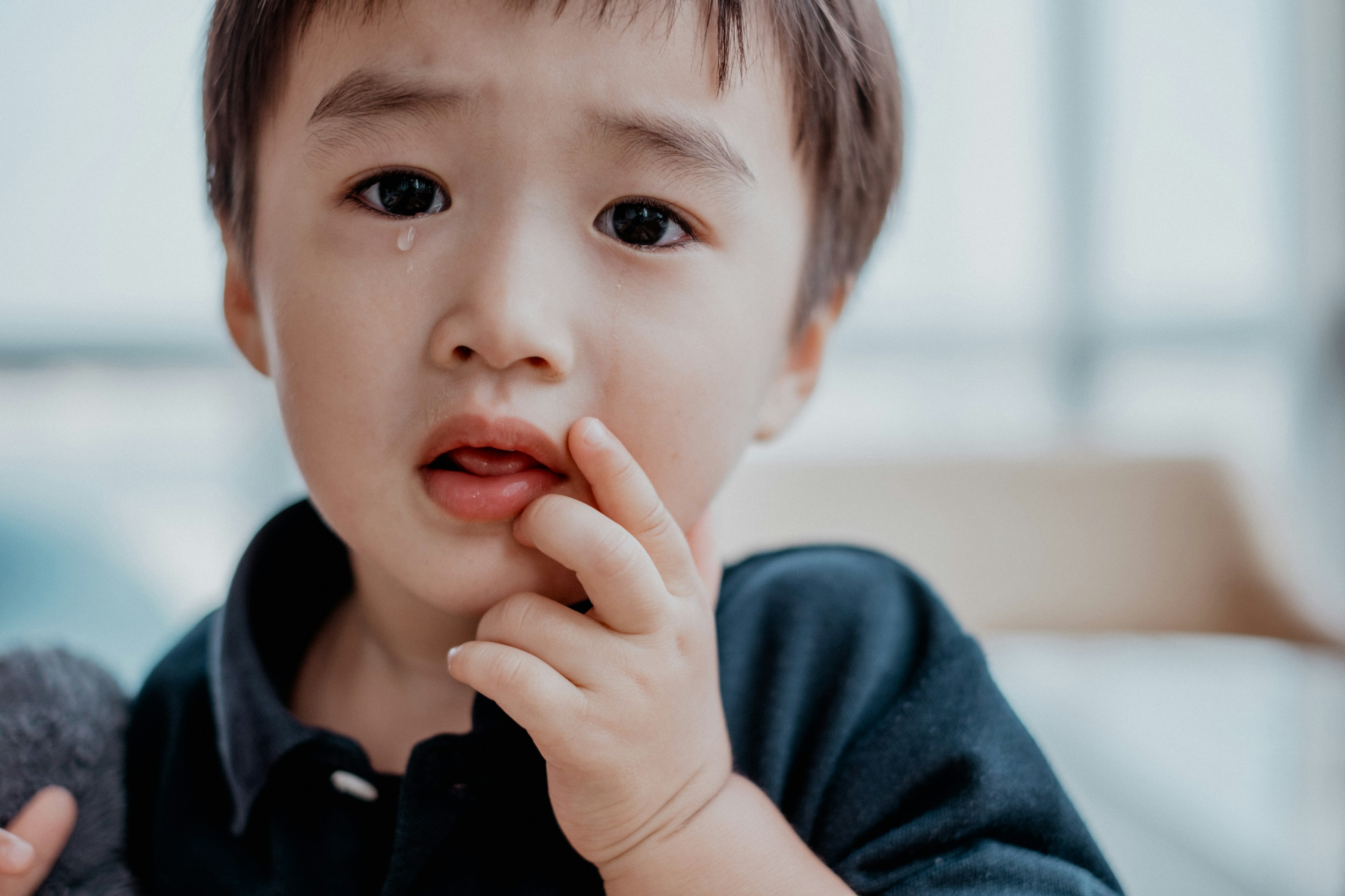 Seorang anak dengan ekspresi khawatir menyentuh mulutnya