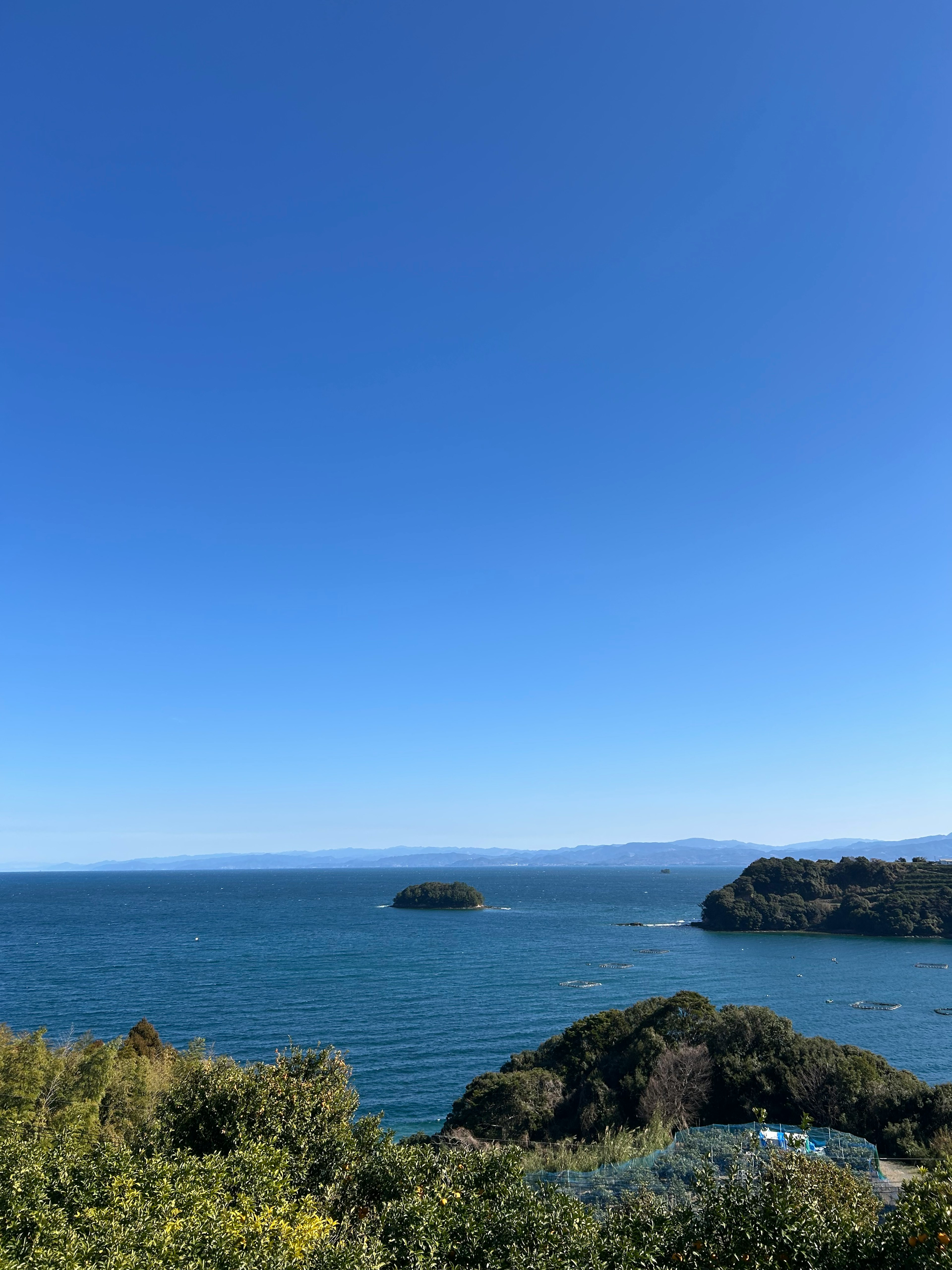 Scenic view of blue sky and ocean with visible islands and greenery