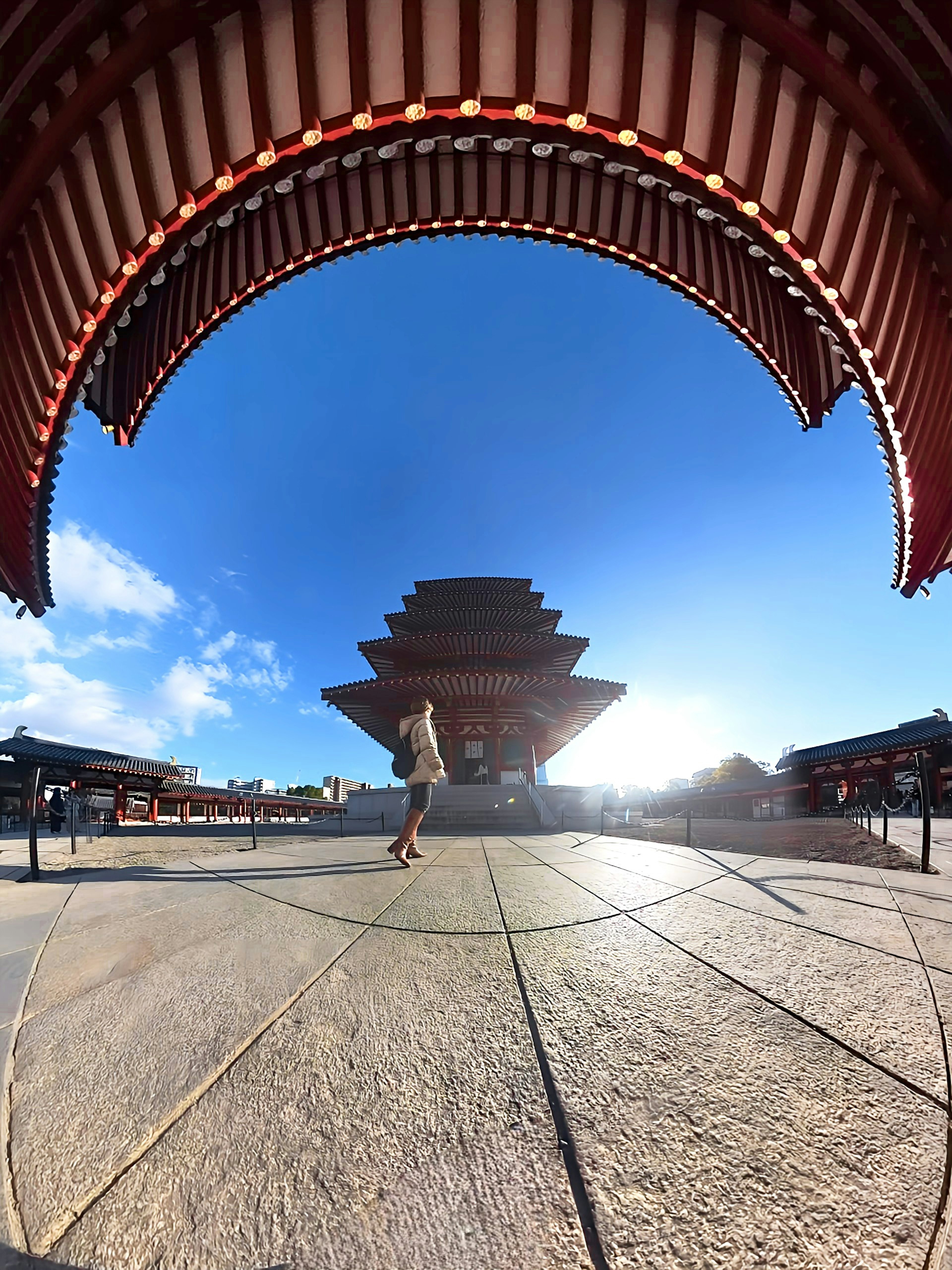 Estructura de templo japonés tradicional bajo un cielo azul con suelo de piedra