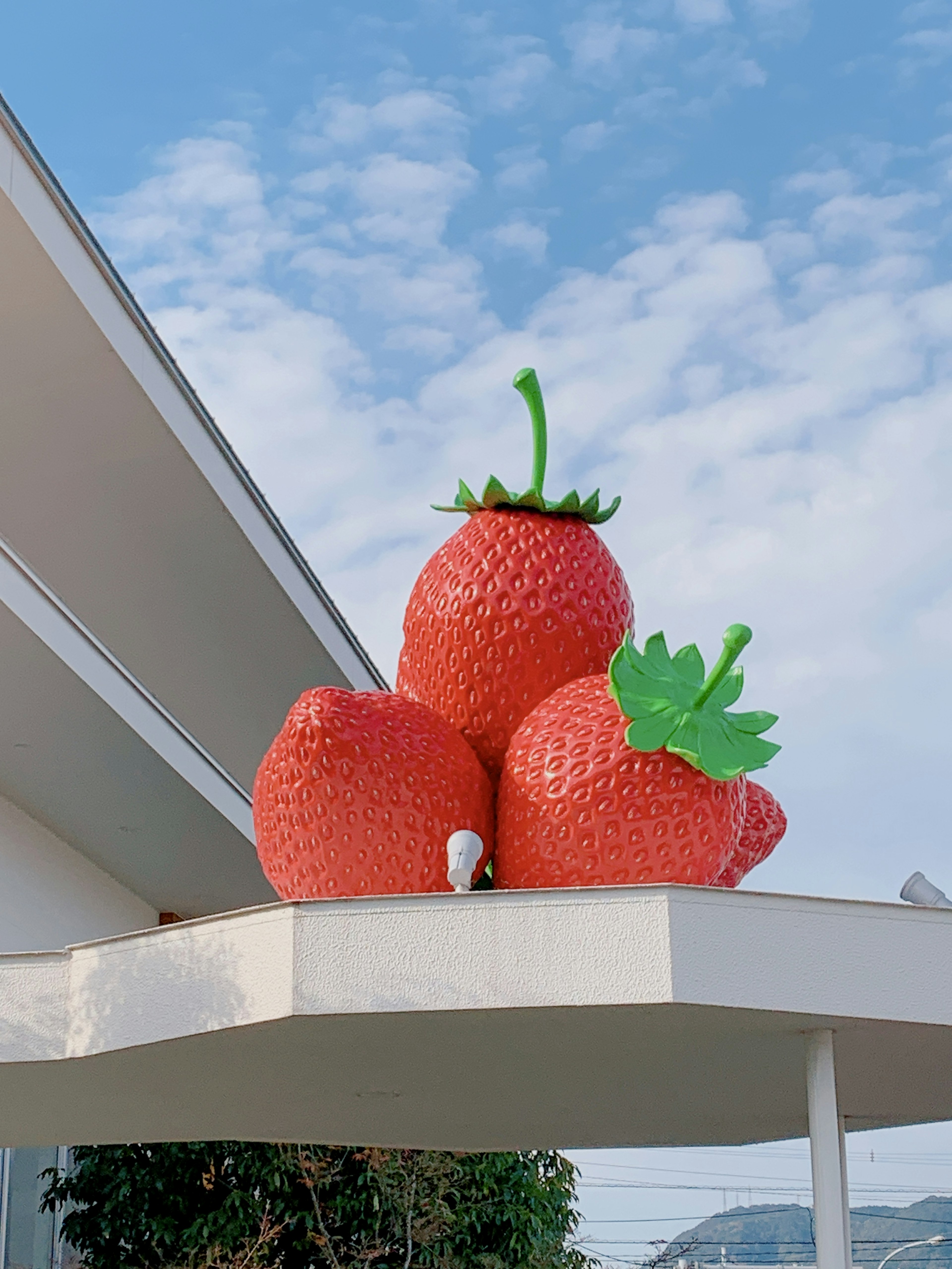 Grandes sculptures de fraises rouges empilées sur un toit