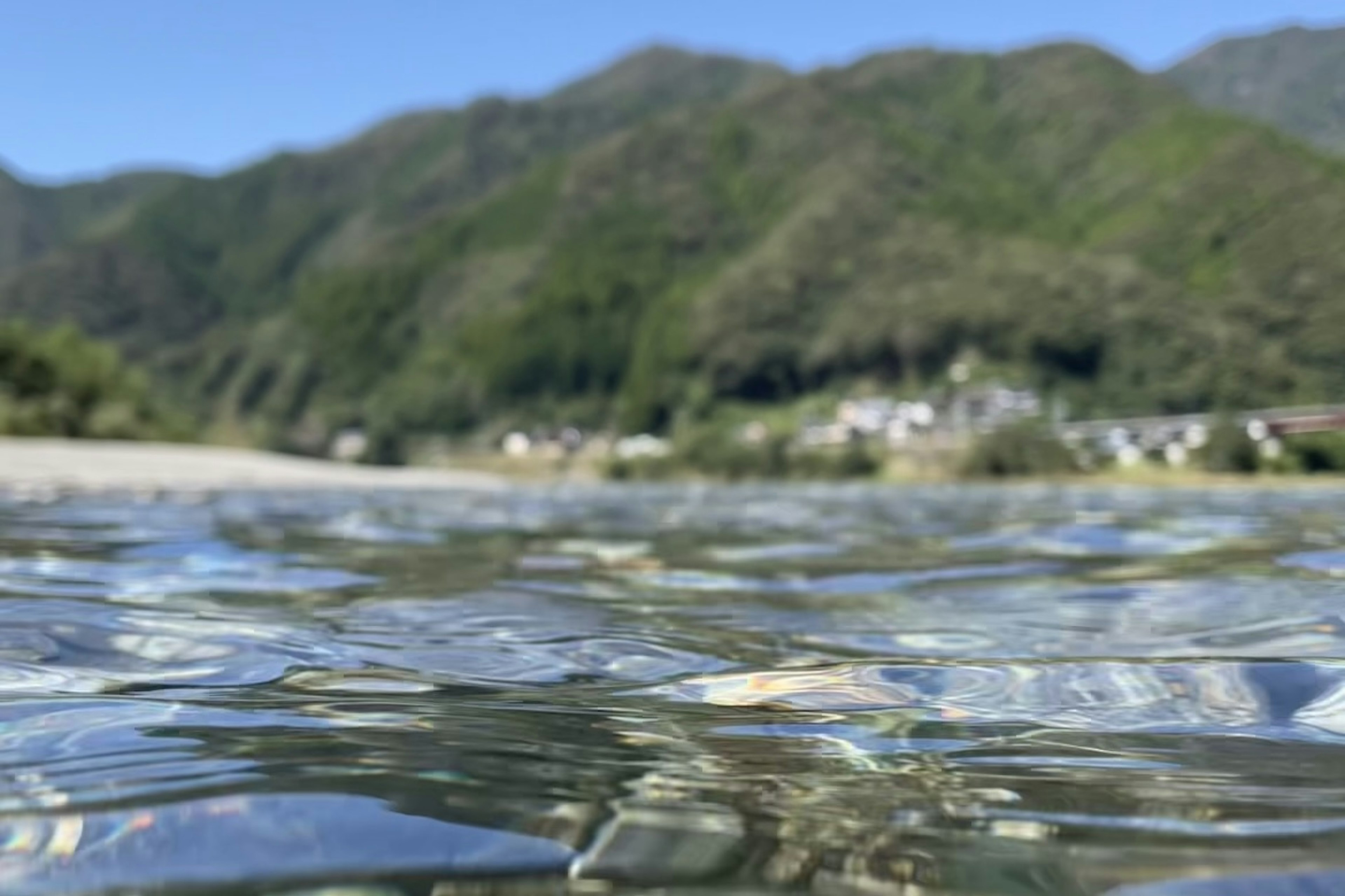 水面下から見た透明な水と緑の山々の風景