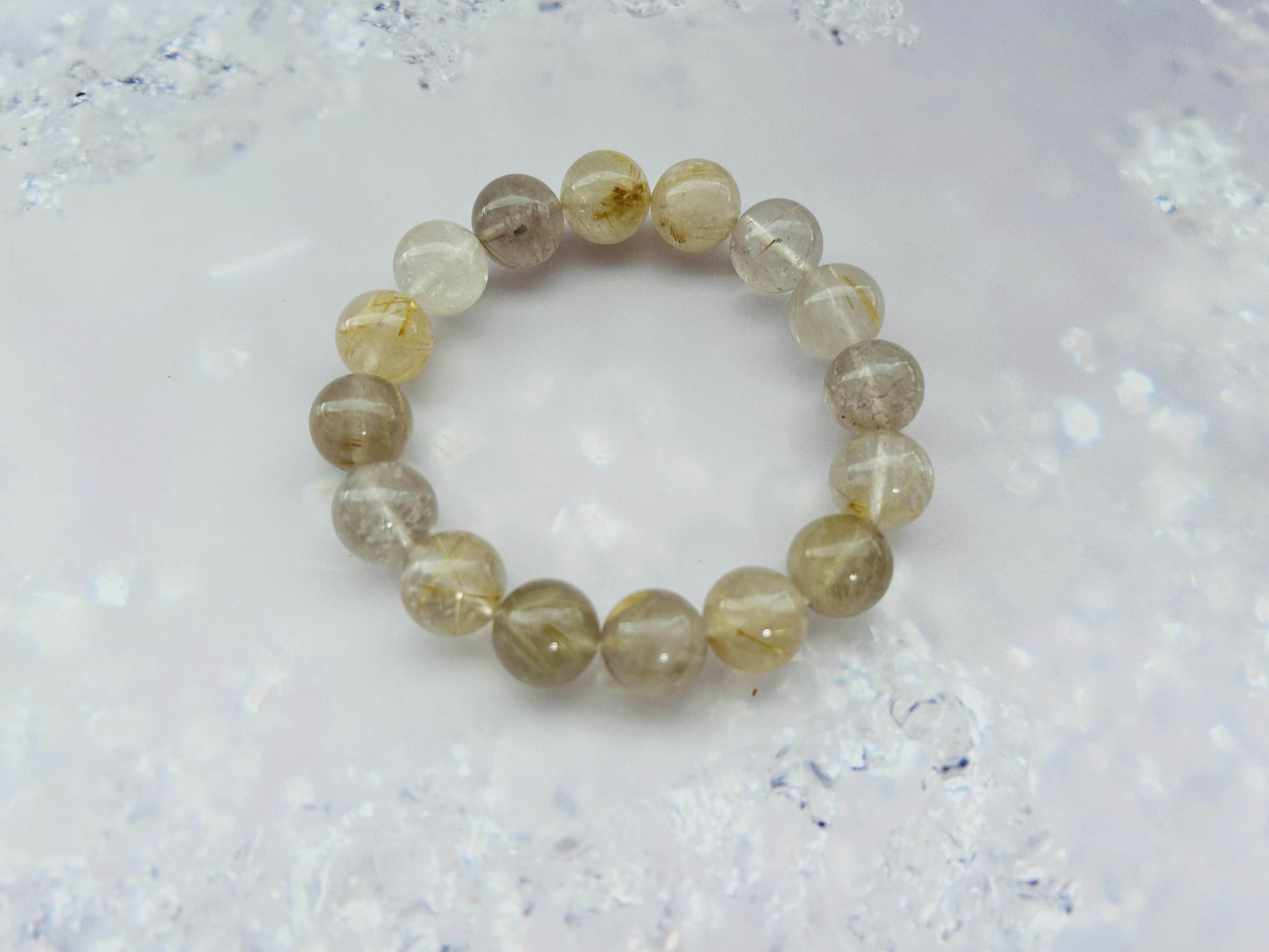 Bracciale in perle di pietra naturale con colori tenui posato su uno sfondo bianco