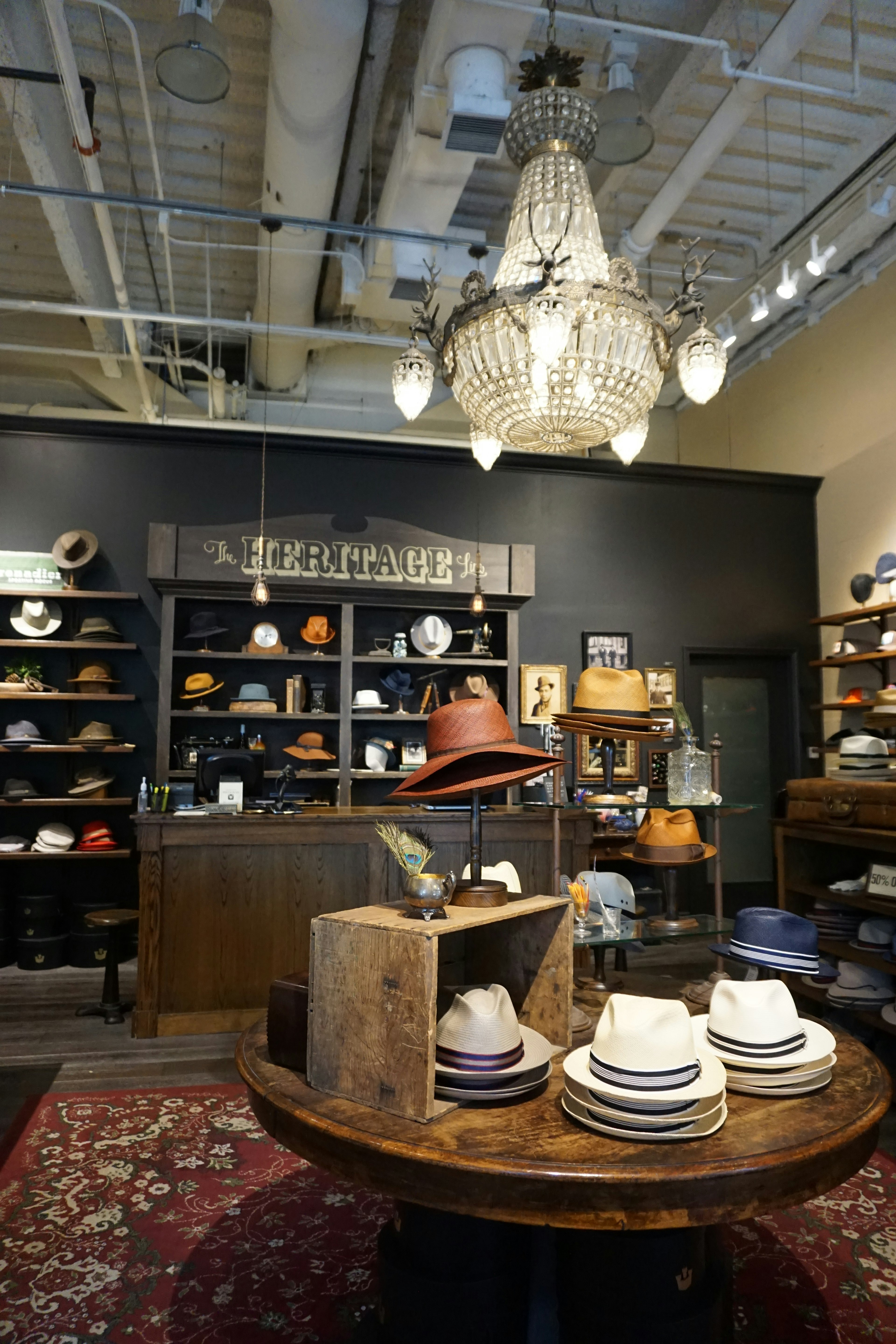 Stylish interior of a store showcasing hats with a chandelier and wooden table