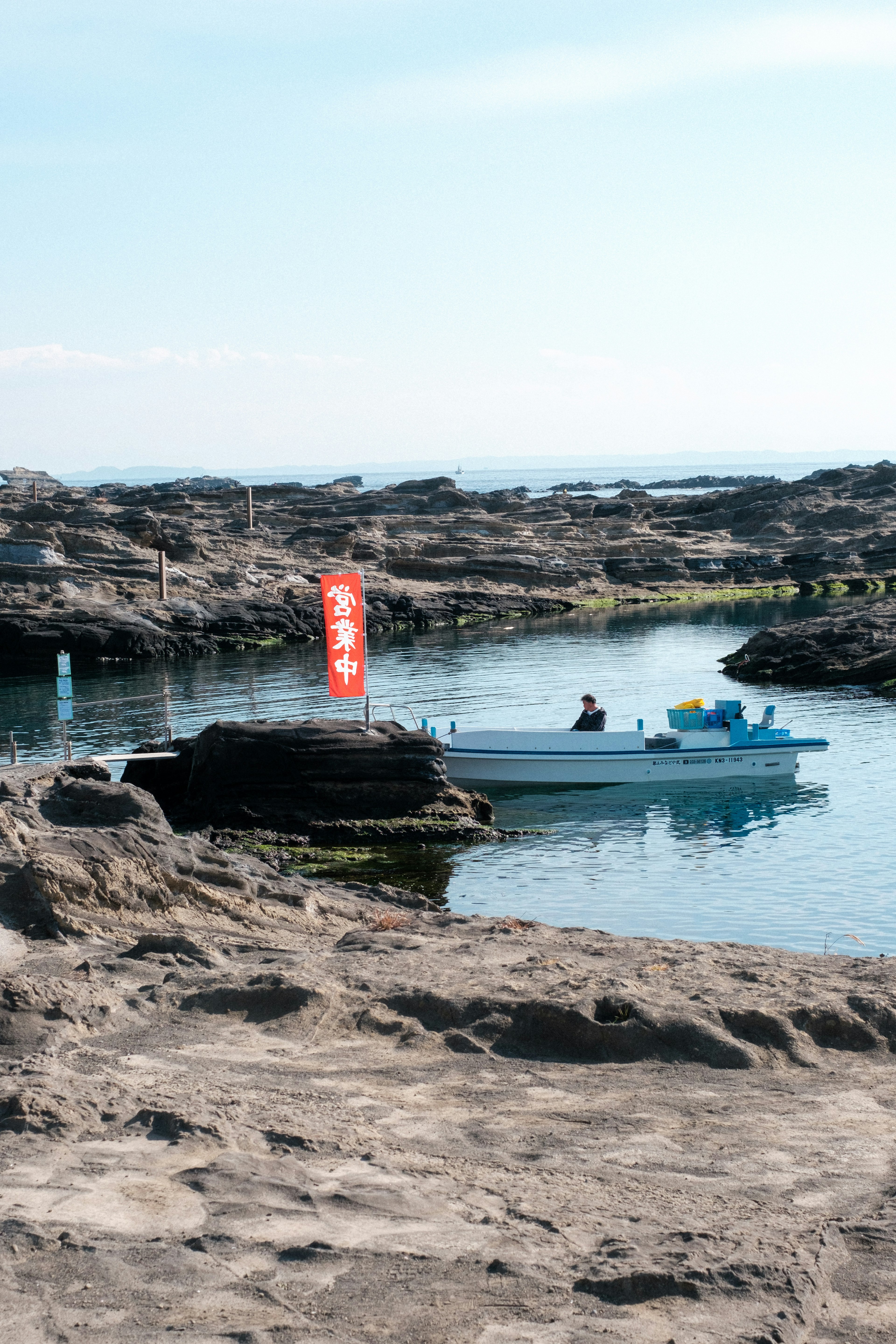 Petit bateau amarré dans une zone rocheuse avec un drapeau rouge