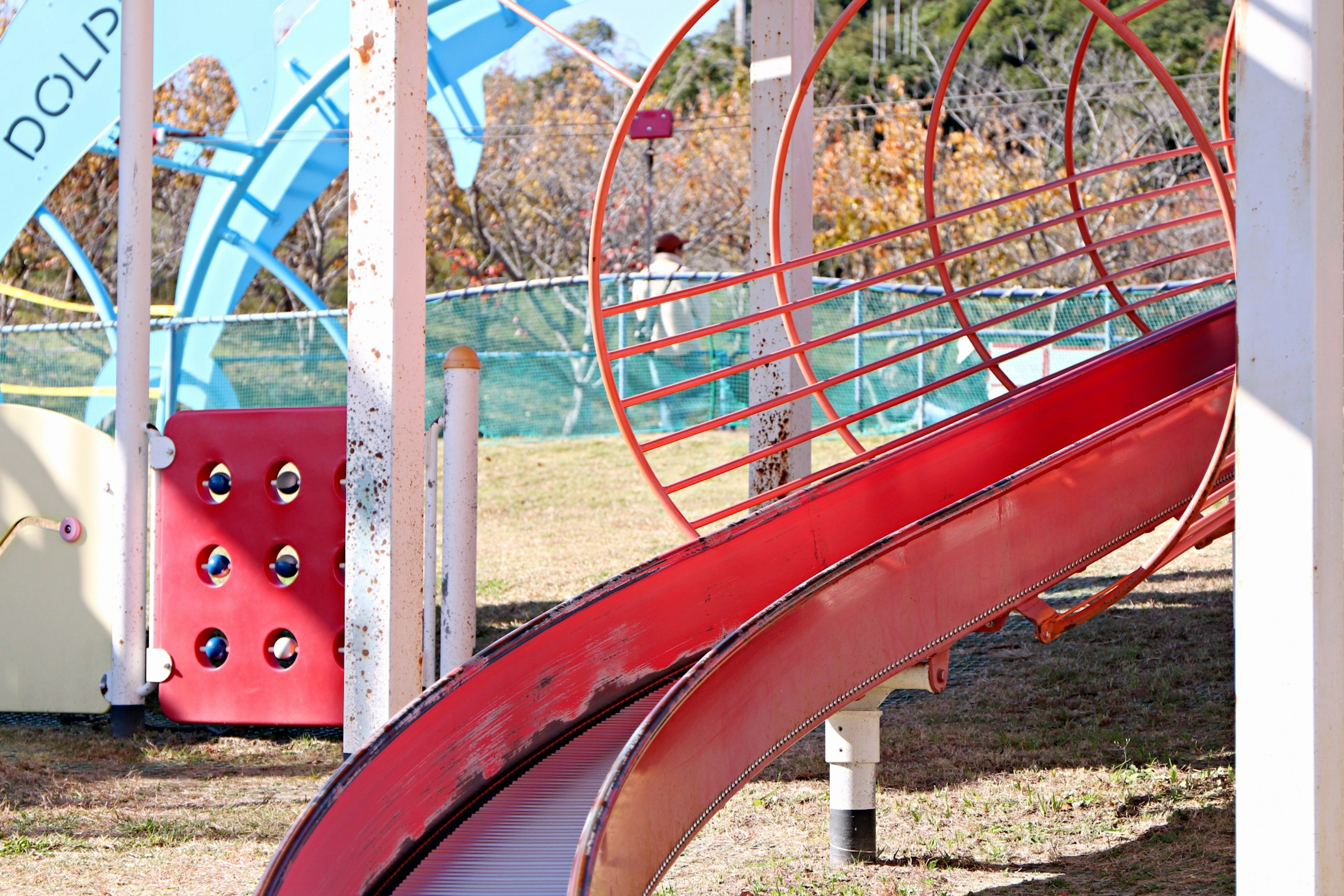 赤い滑り台と青い遊具がある公園の遊び場