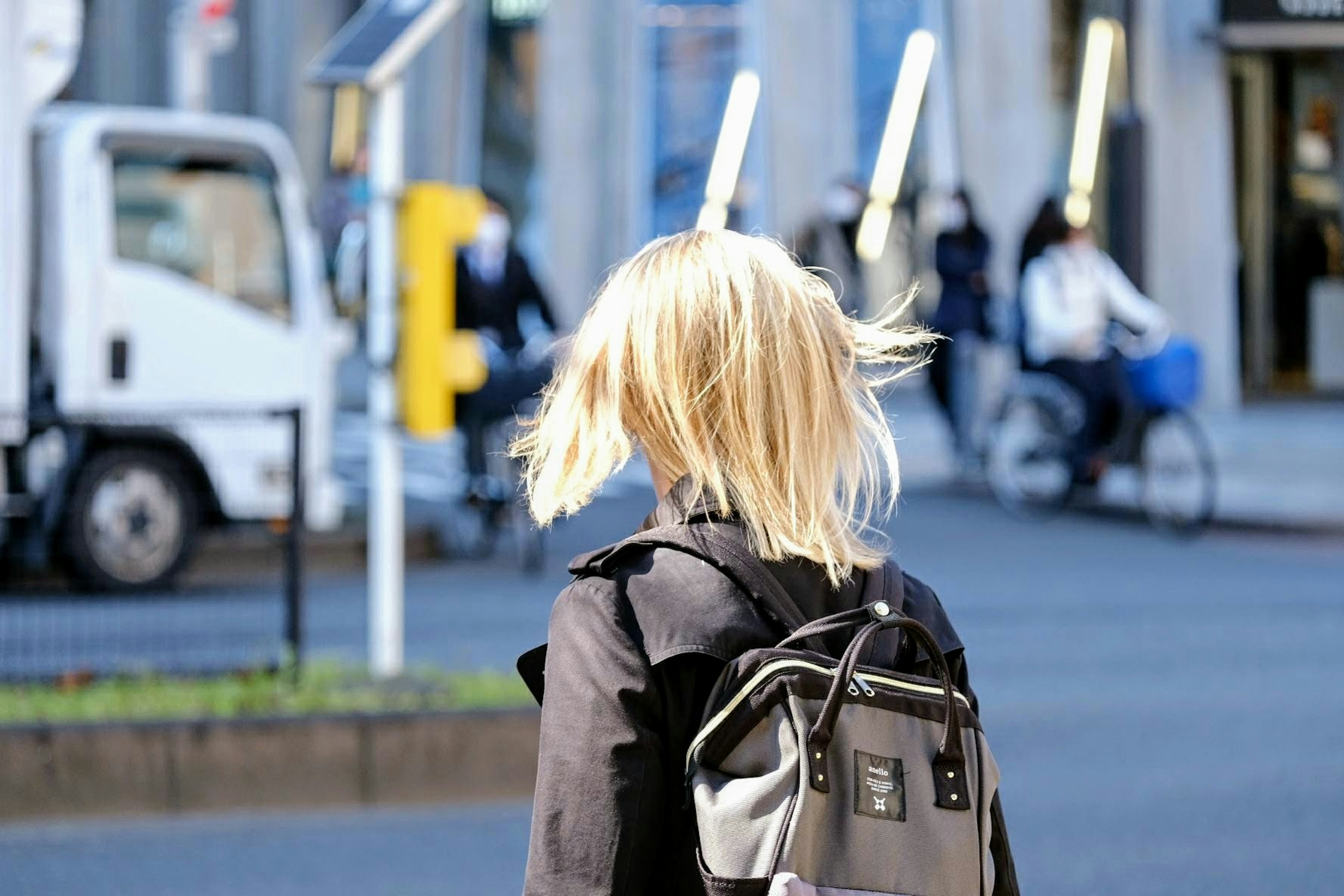 髪が風になびく女性の後ろ姿と街の風景