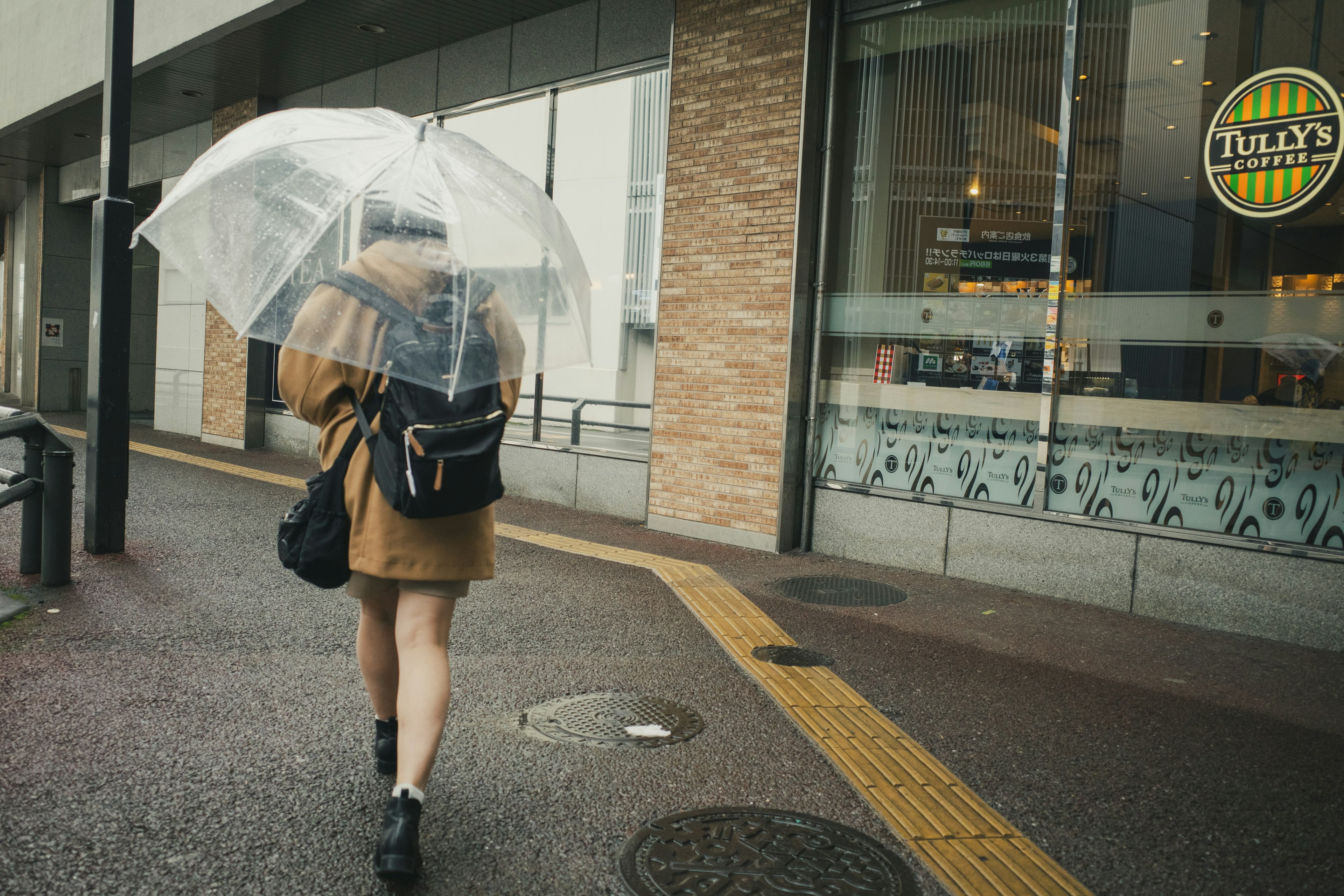 Frau, die mit einem transparenten Regenschirm und lässiger Kleidung geht