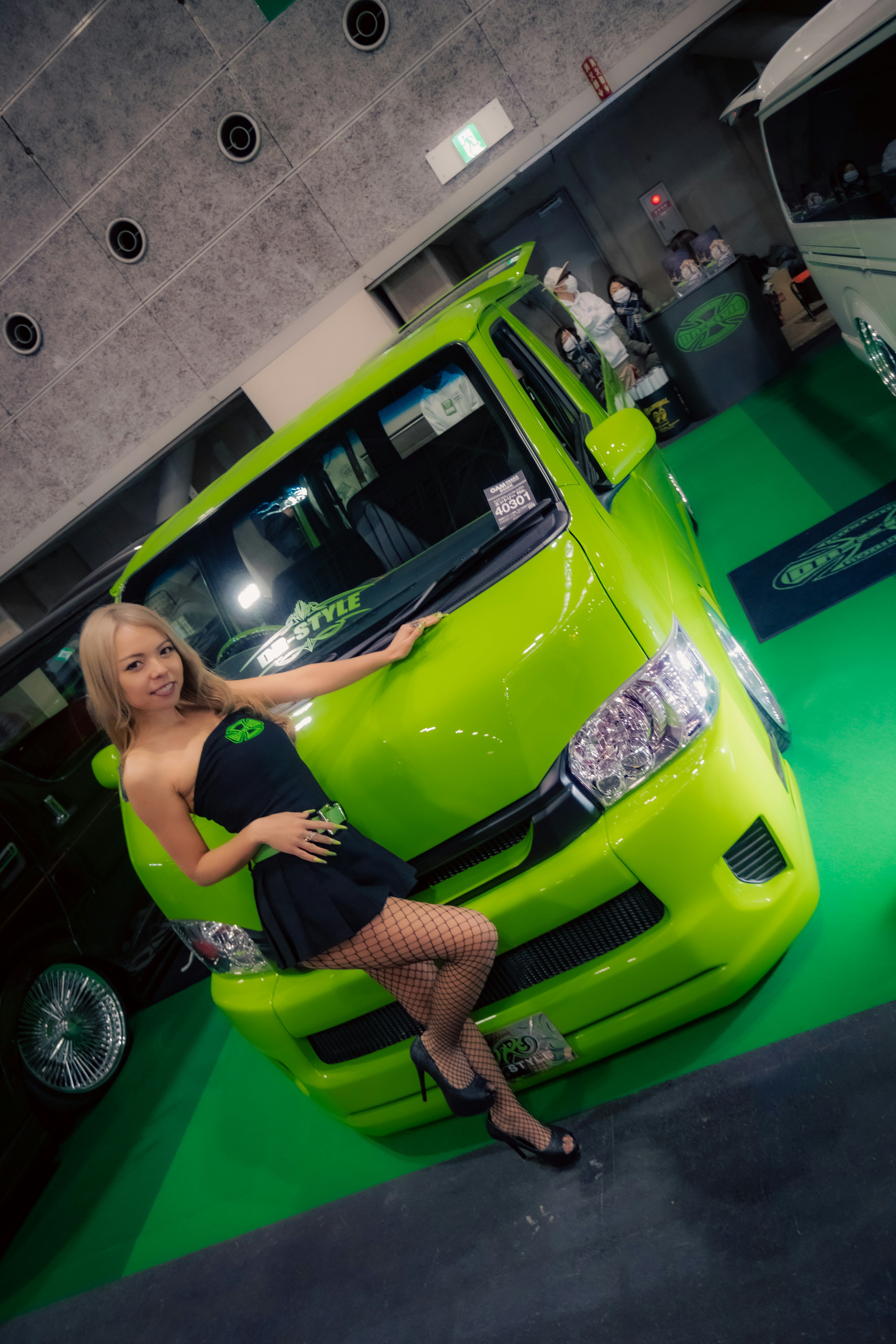 A woman posing in front of a vibrant green vehicle