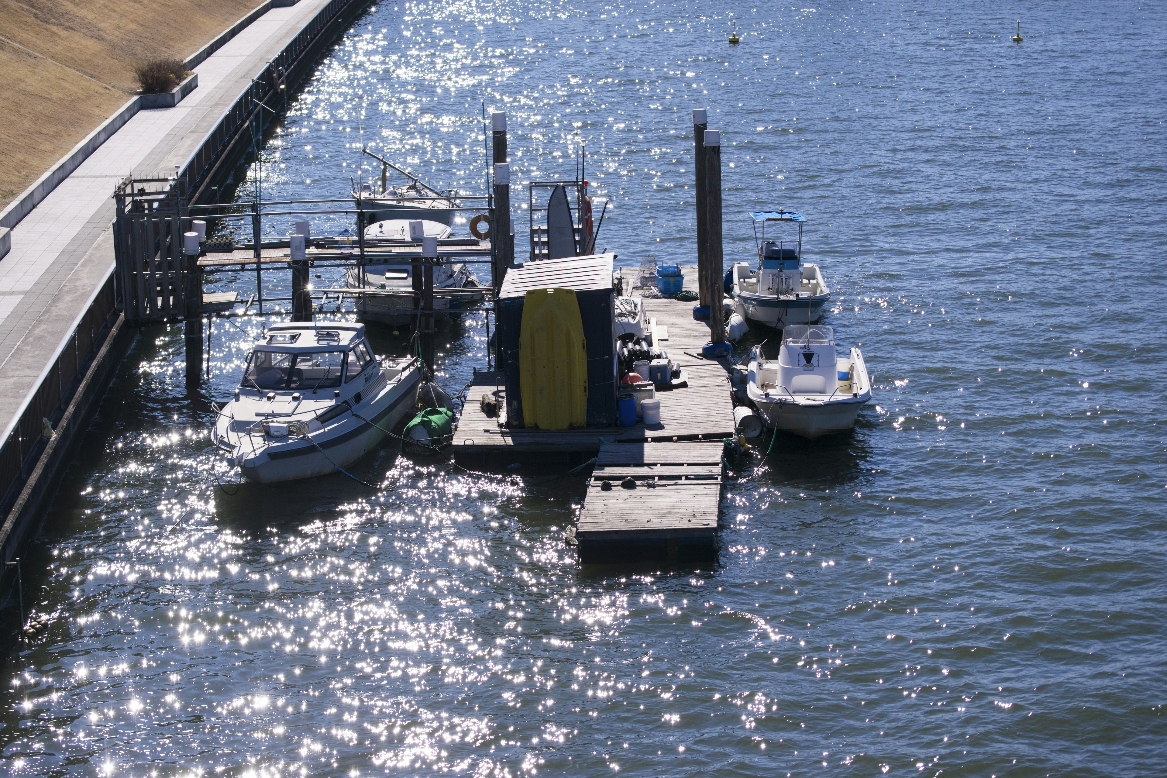 Boote an einem schwimmenden Steg auf schimmerndem Wasser