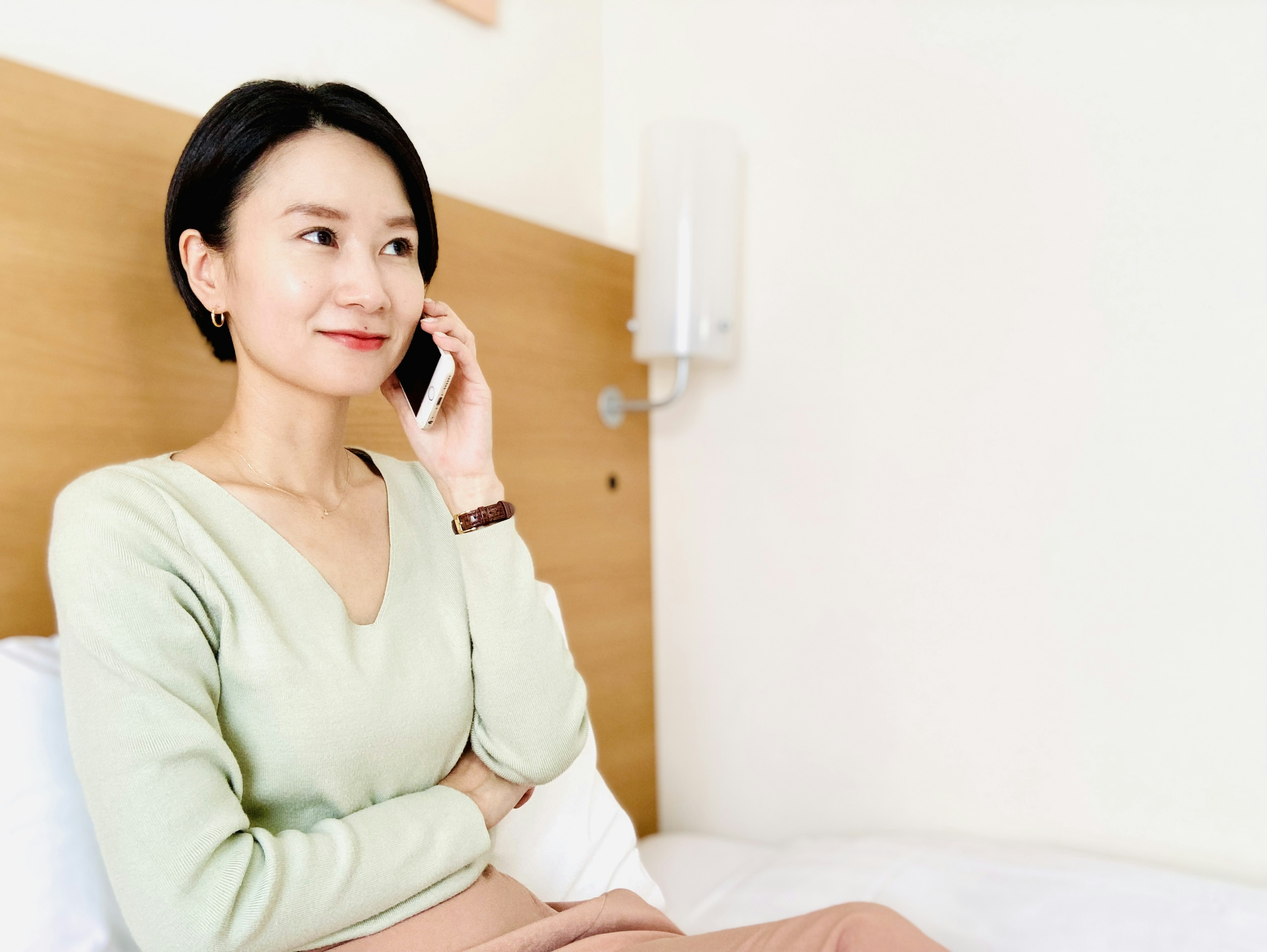 Une femme au téléphone avec une expression calme portant une tenue de couleur douce