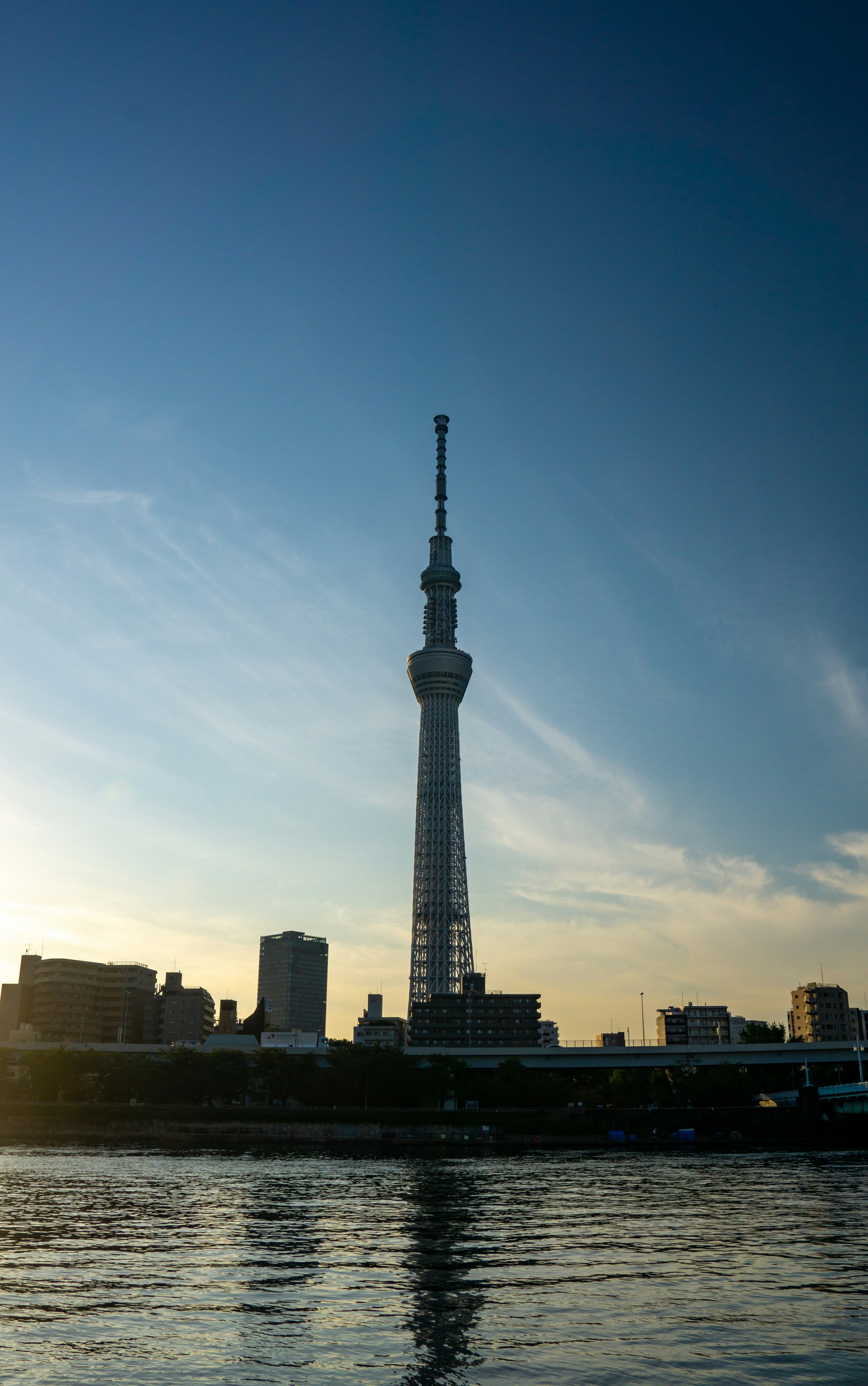 東京スカイツリーのシルエットが水面に映る夕暮れの風景