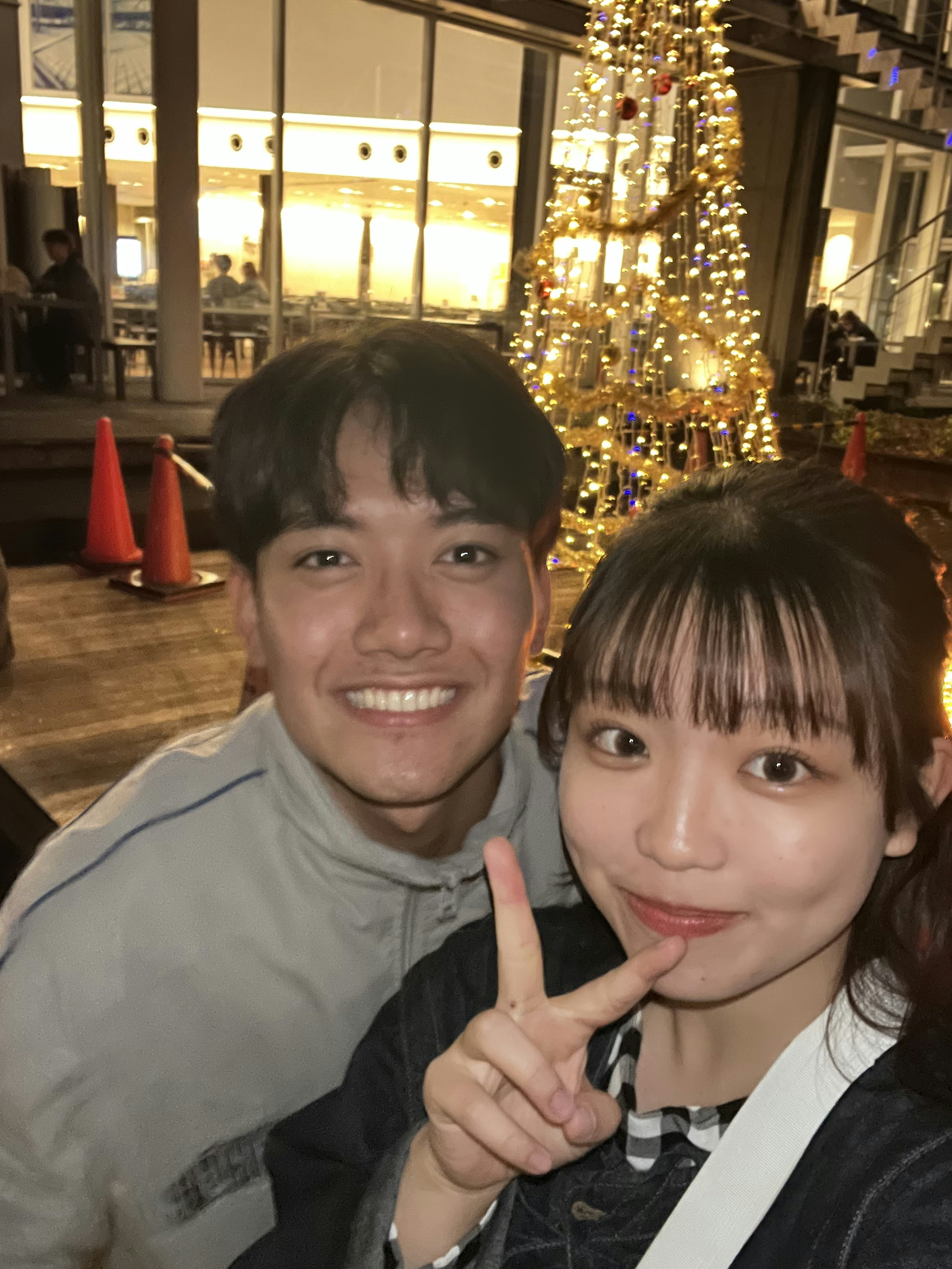 Smiling young couple posing in front of a Christmas tree