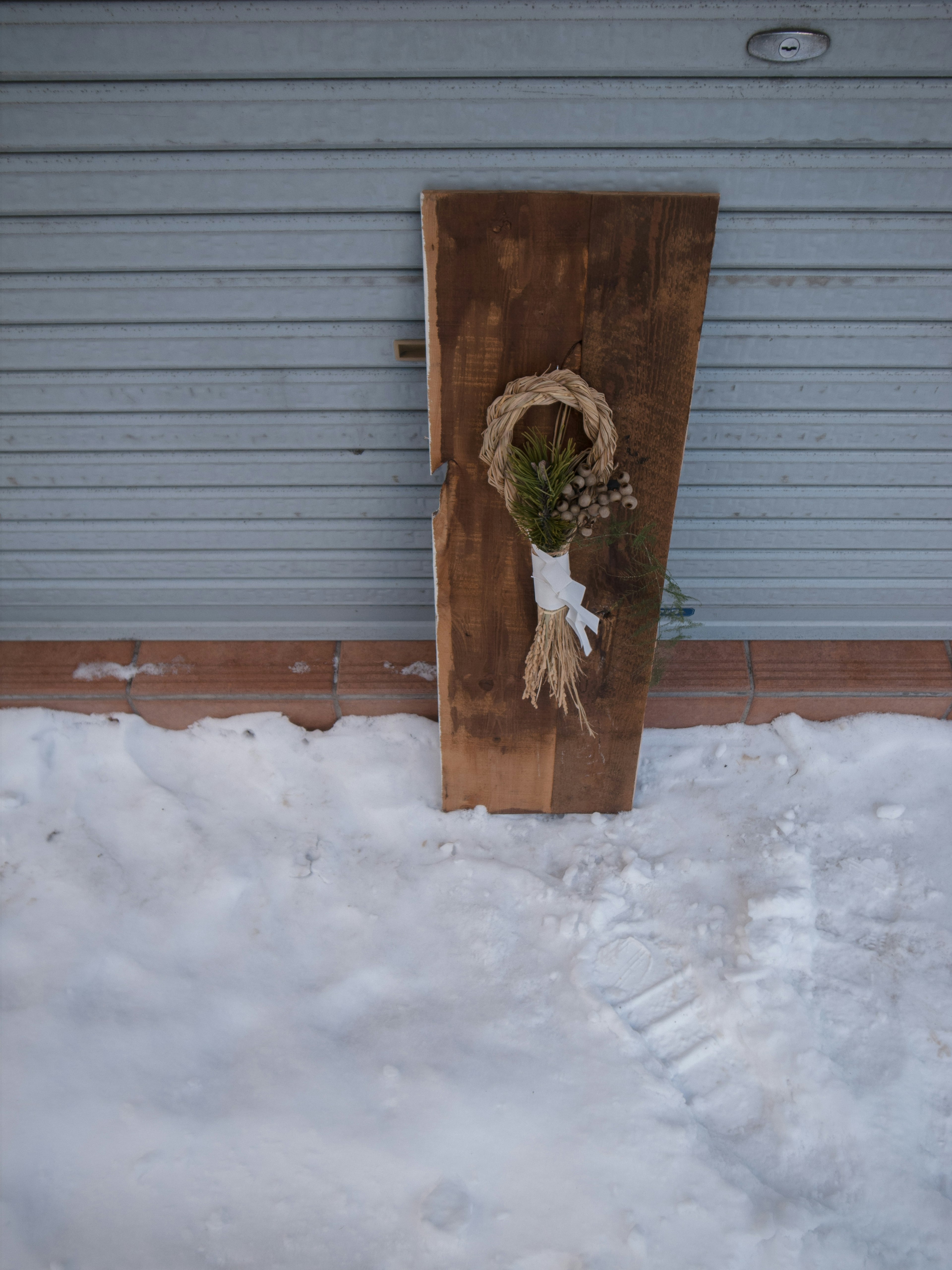 Holzbrett dekoriert mit natürlichen Elementen auf schneebedecktem Boden