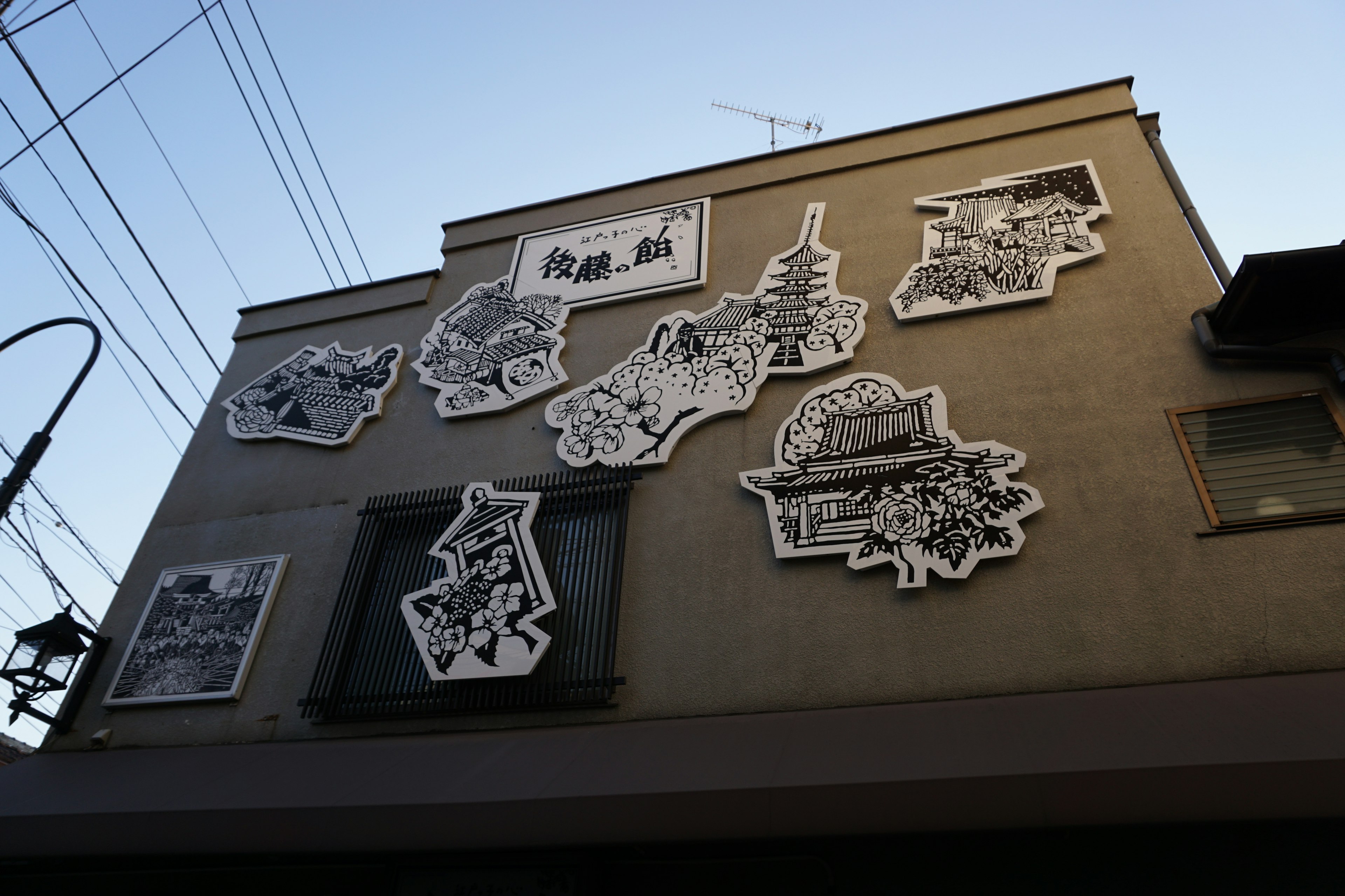 Building exterior adorned with white illustrations featuring various artistic designs