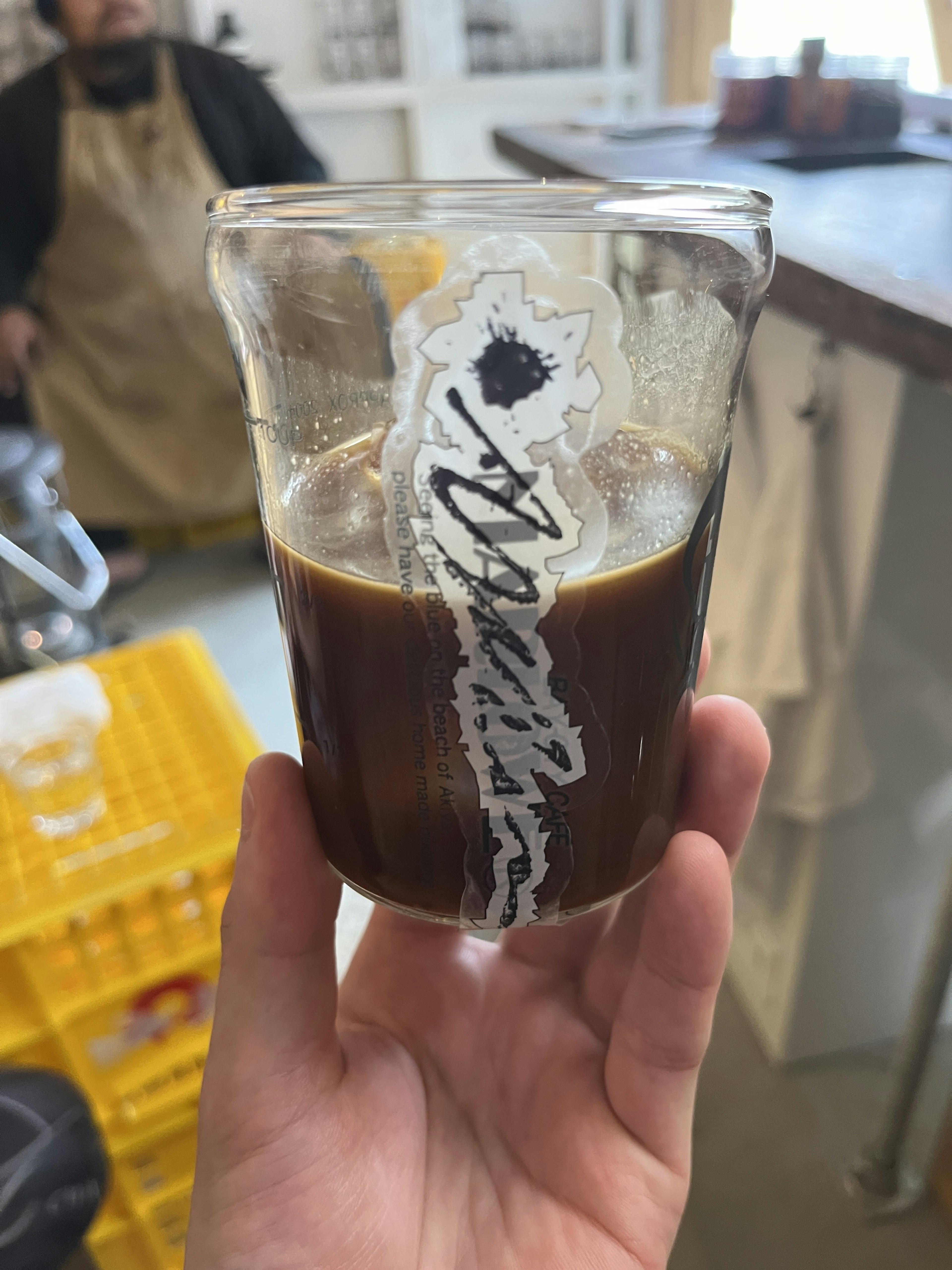 手に持たれたコーヒーカップに濃いコーヒーが入っている