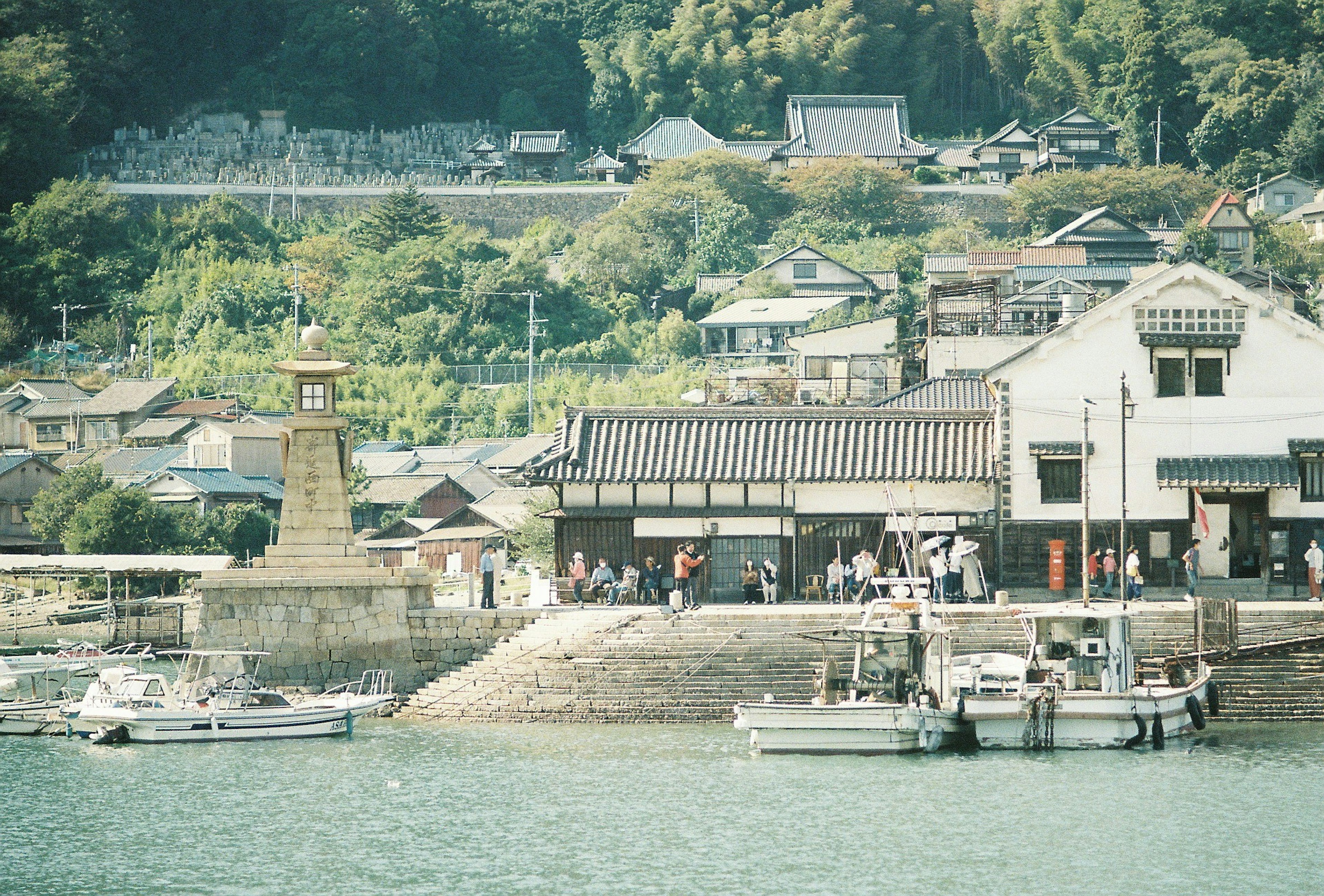 穏やかな海に面した古い港町の風景で人々が集まる岸辺と歴史的な建物が見られる