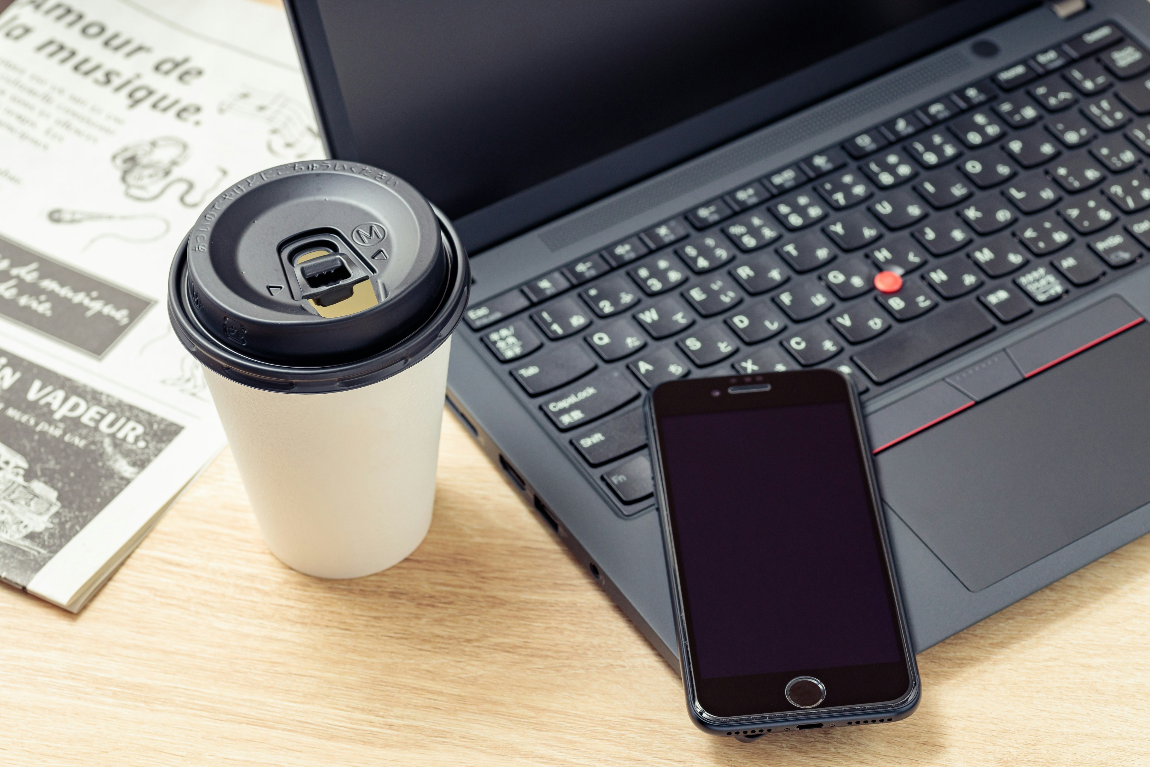 Scene of a desk with a laptop coffee cup smartphone and newspaper