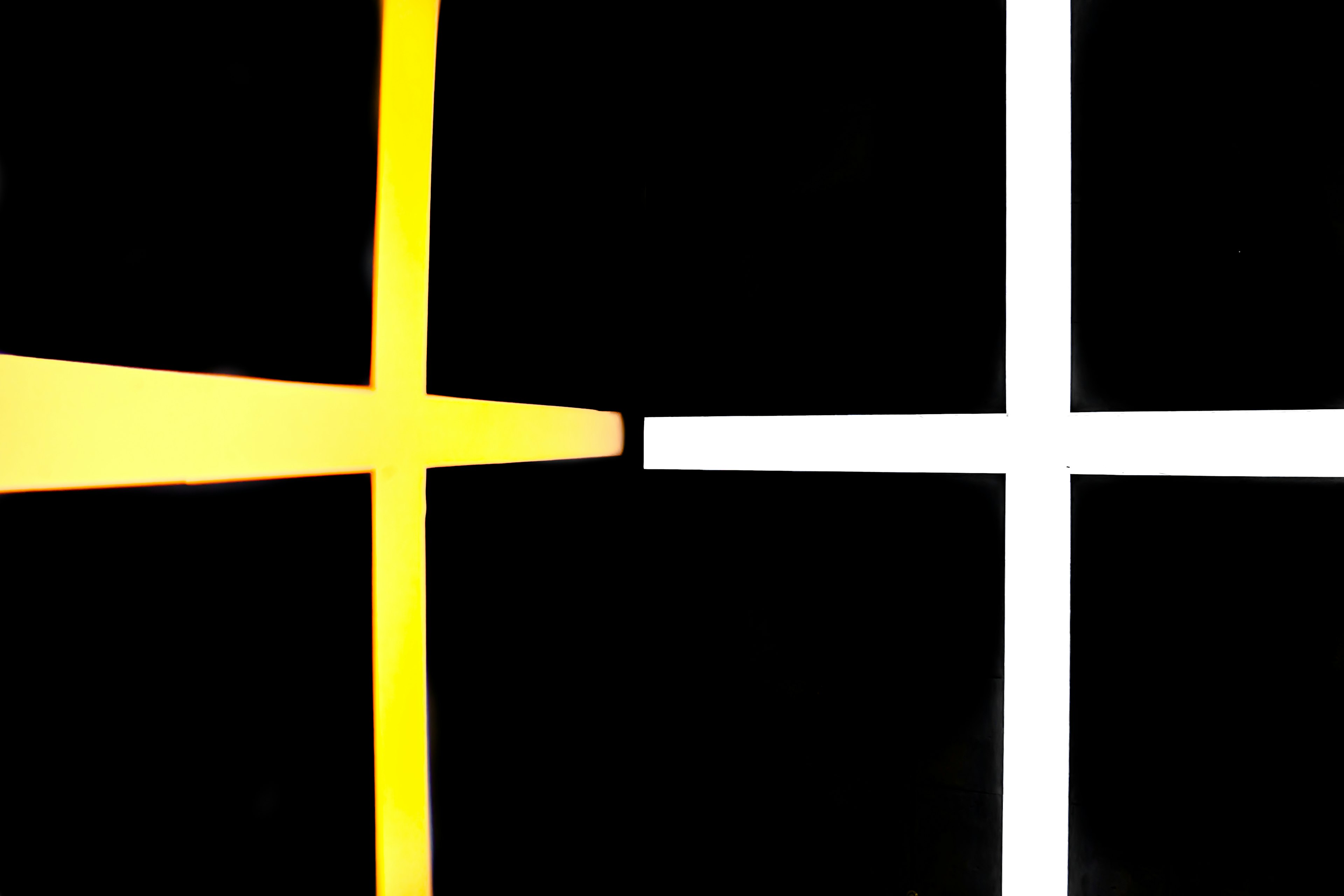 Simple design featuring intersecting yellow and white crosses on a black background