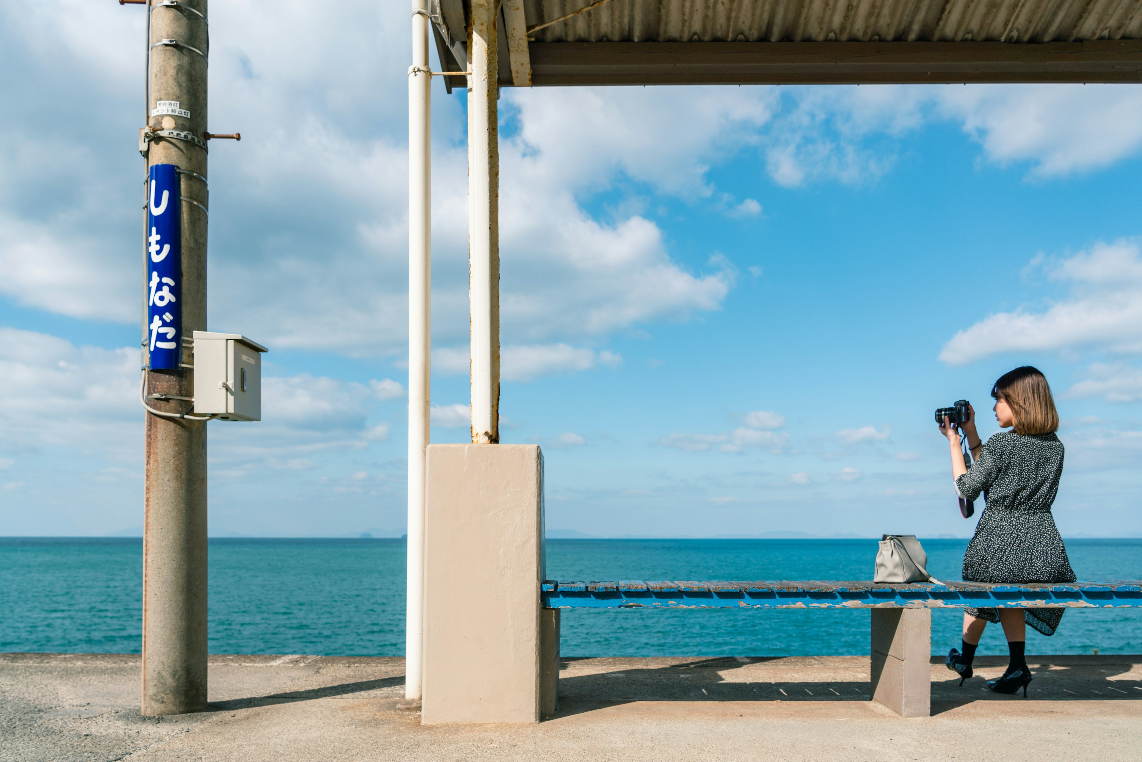 Femme prenant des photos avec un appareil photo sur un banc au bord de la mer