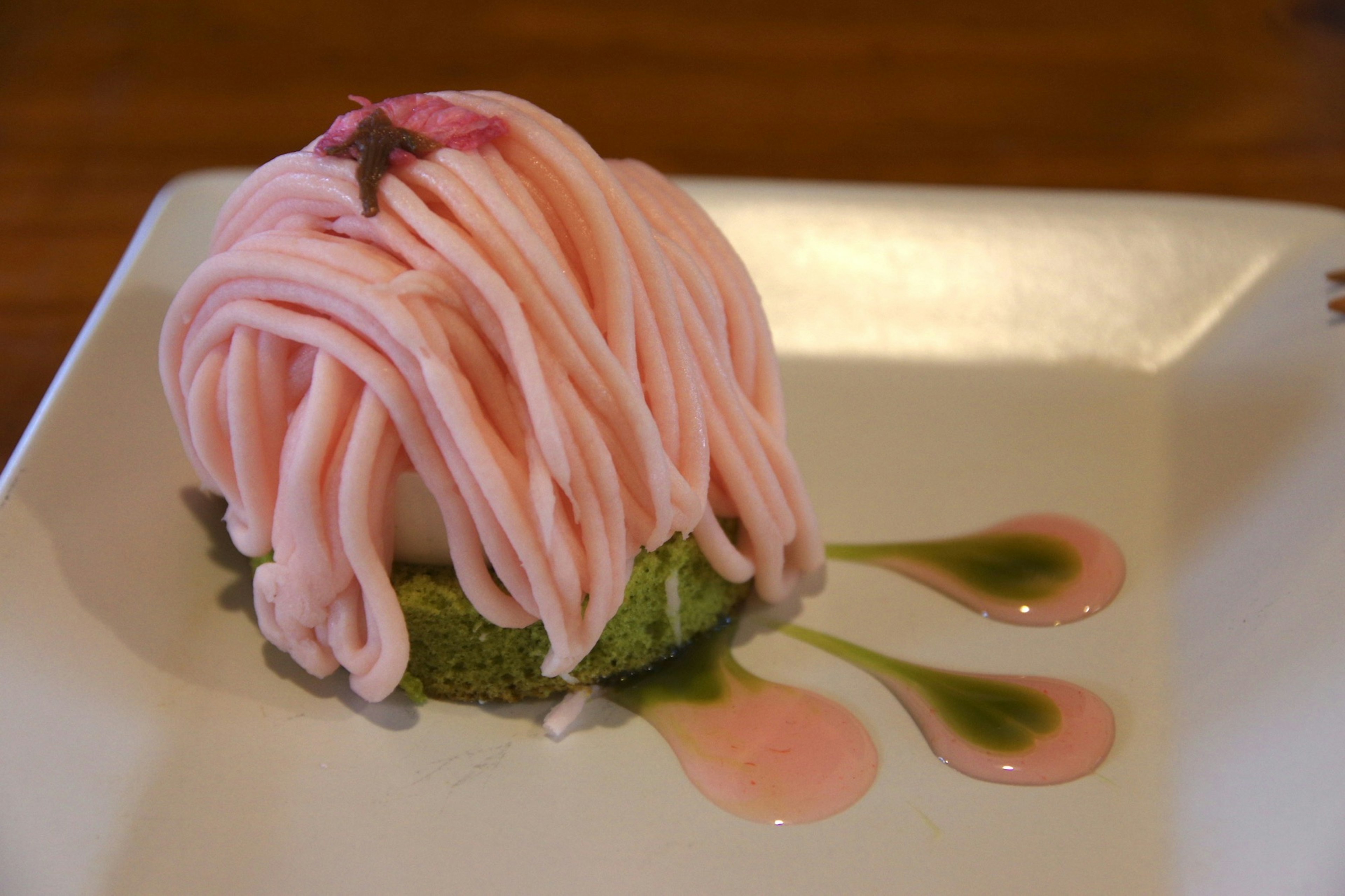 Postre de castaña rosa con un diseño floral sobre una base verde