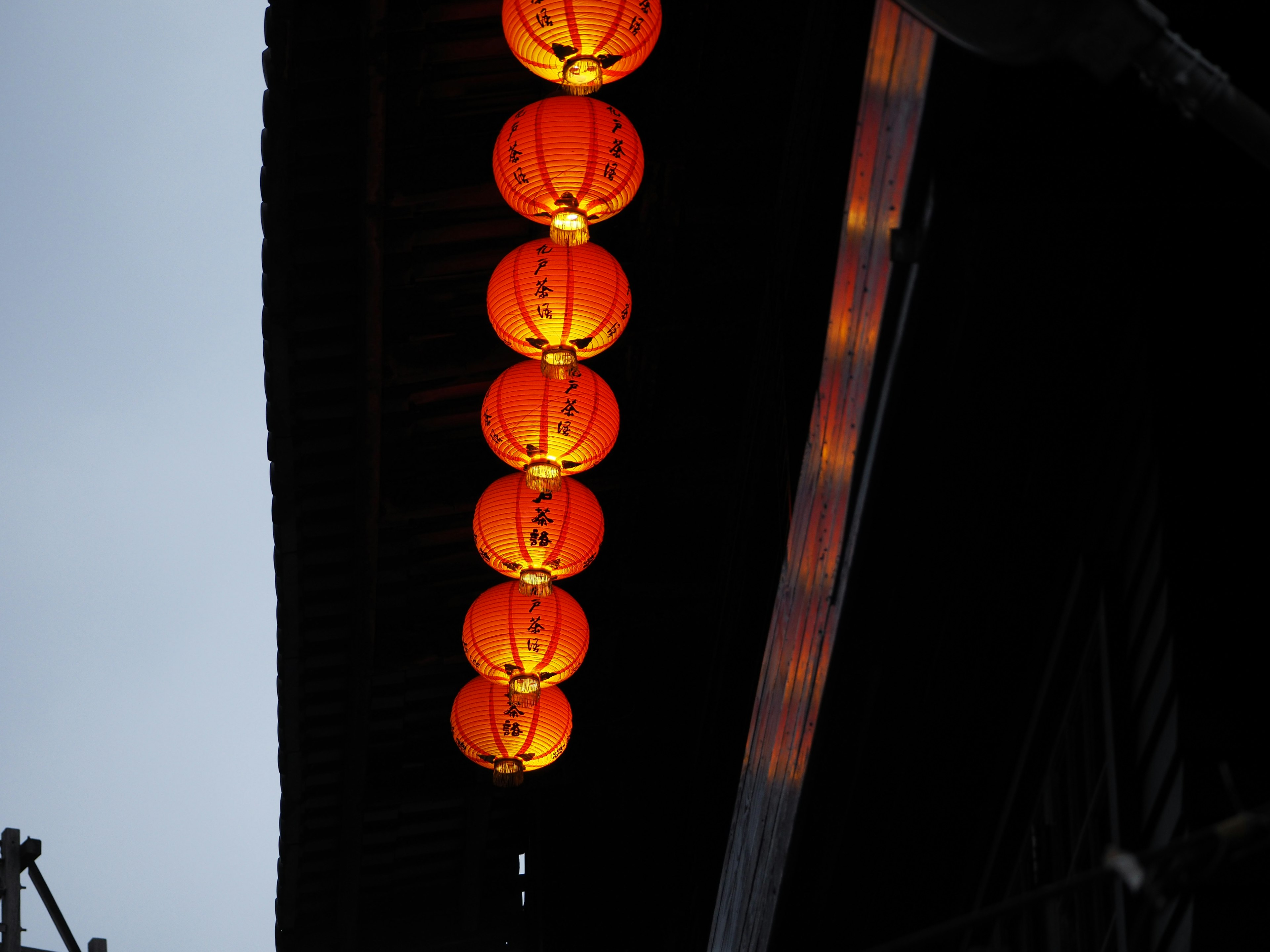 Une rangée de lanternes orange suspendues à un toit