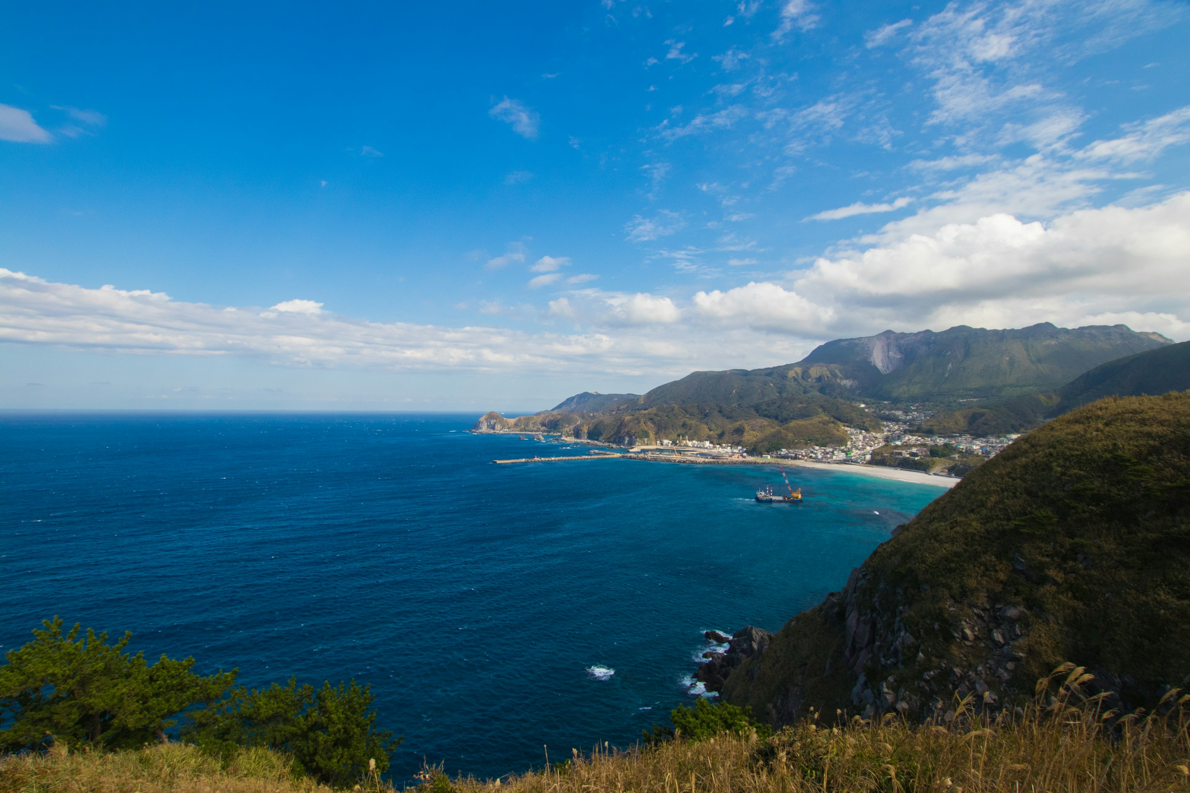 Scenic coastal view featuring blue ocean and sky with mountains in the background