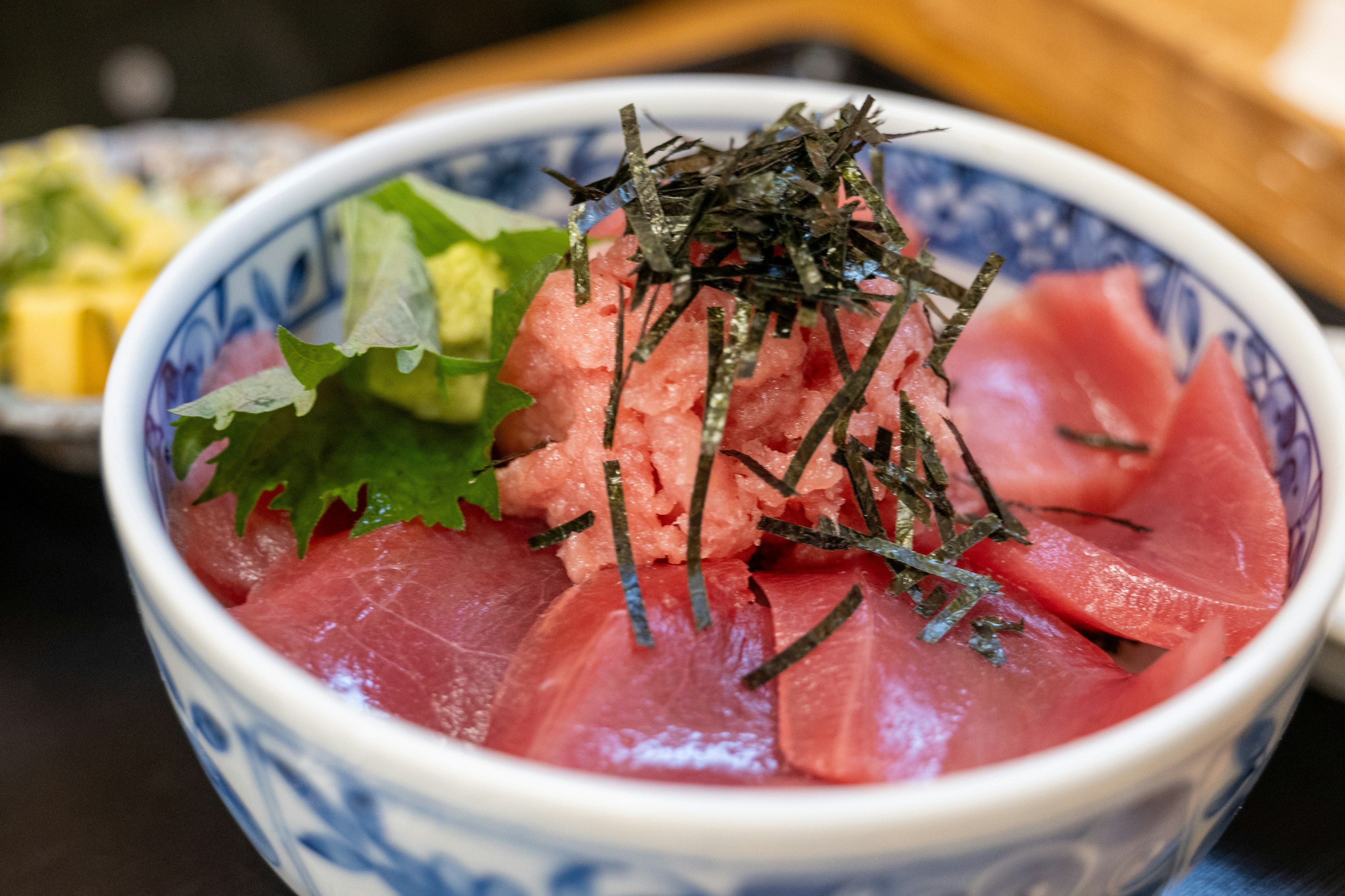 Bowl of fresh tuna sashimi topped with wasabi and seaweed