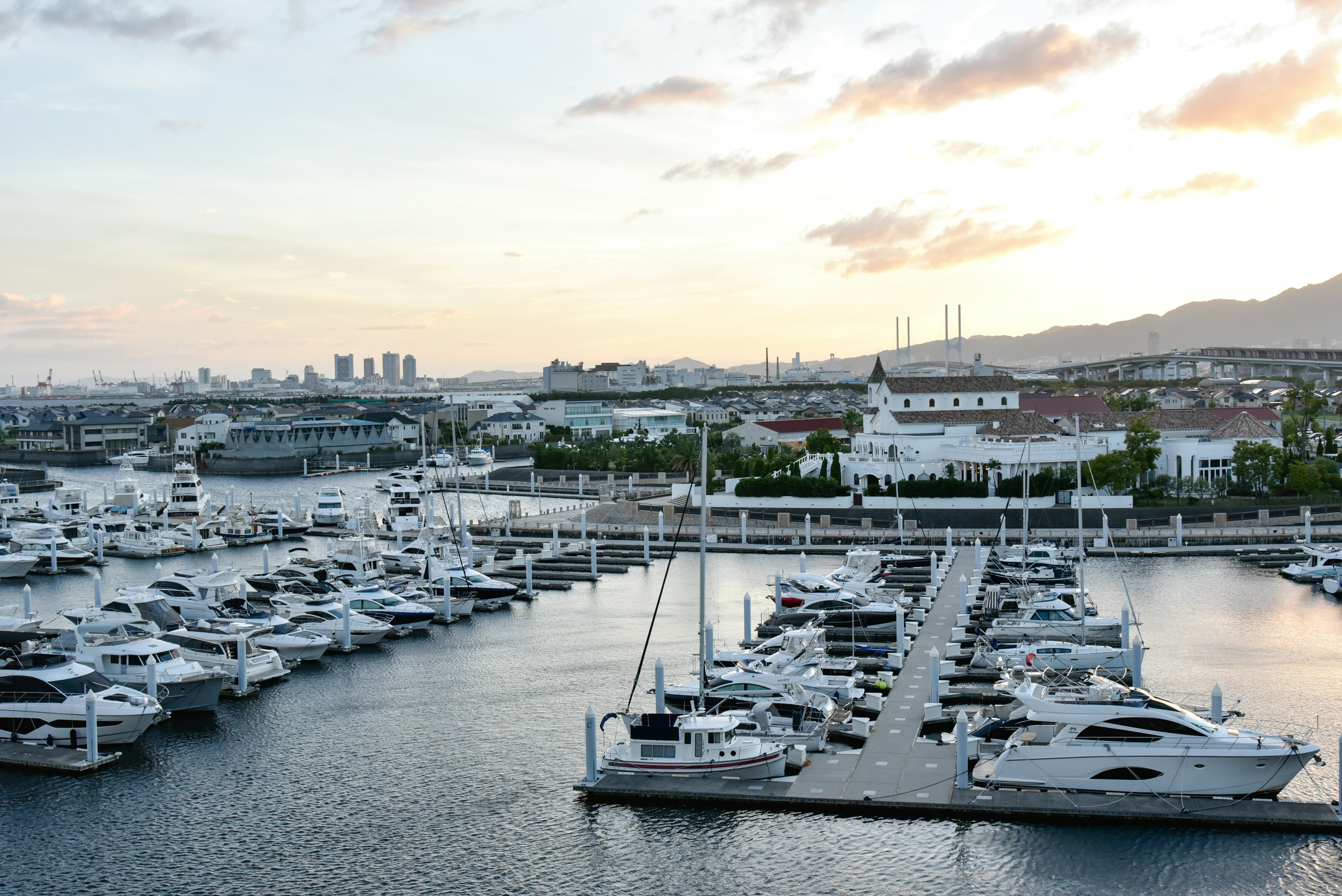 Malersicher Blick auf eine Marina mit Yachten bei Sonnenuntergang und modernen Gebäuden im Hintergrund