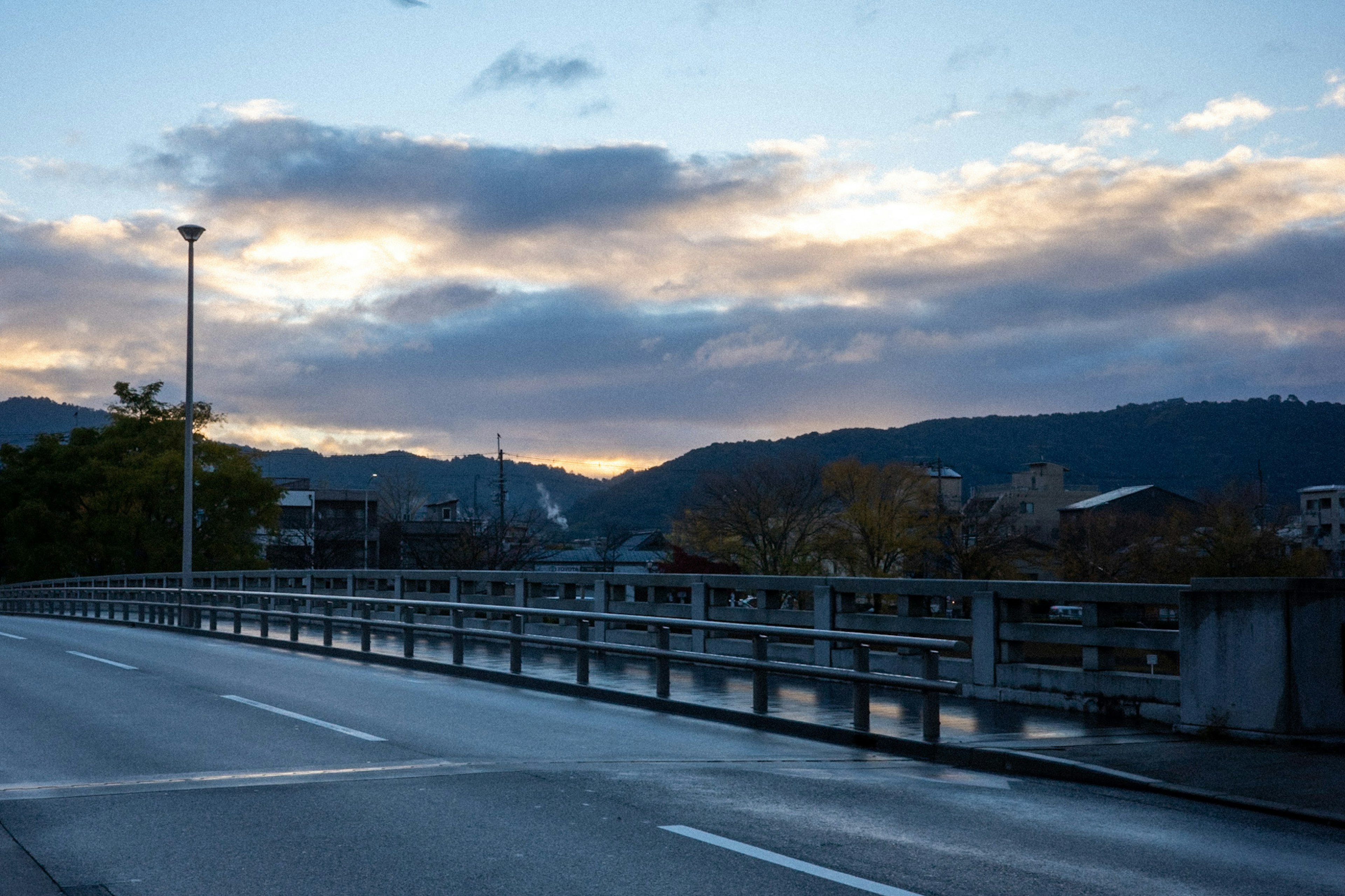 Scenic view of a bridge at dusk with mountains in the background