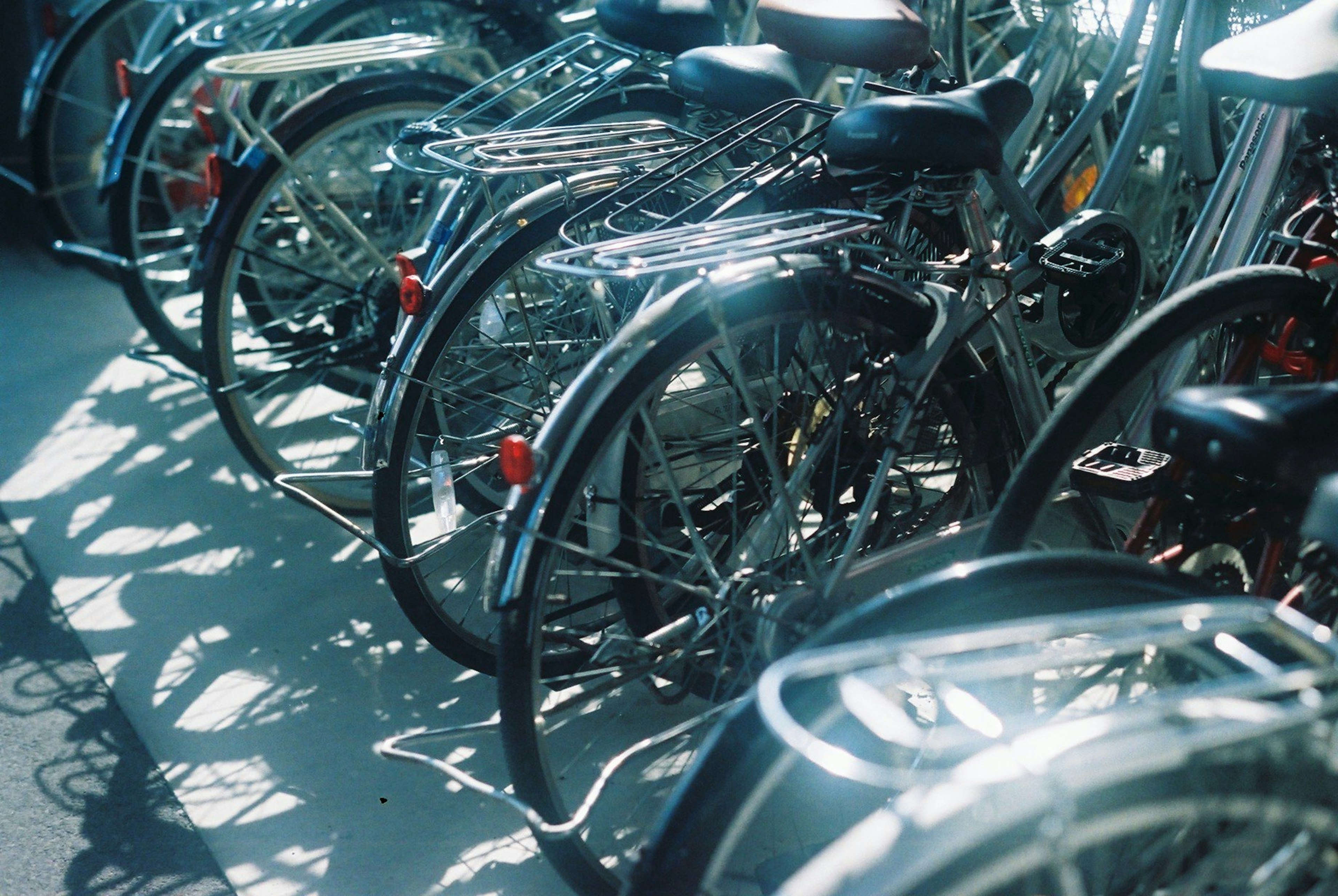 Bicycles with shiny metal frames and wheels casting shadows in sunlight