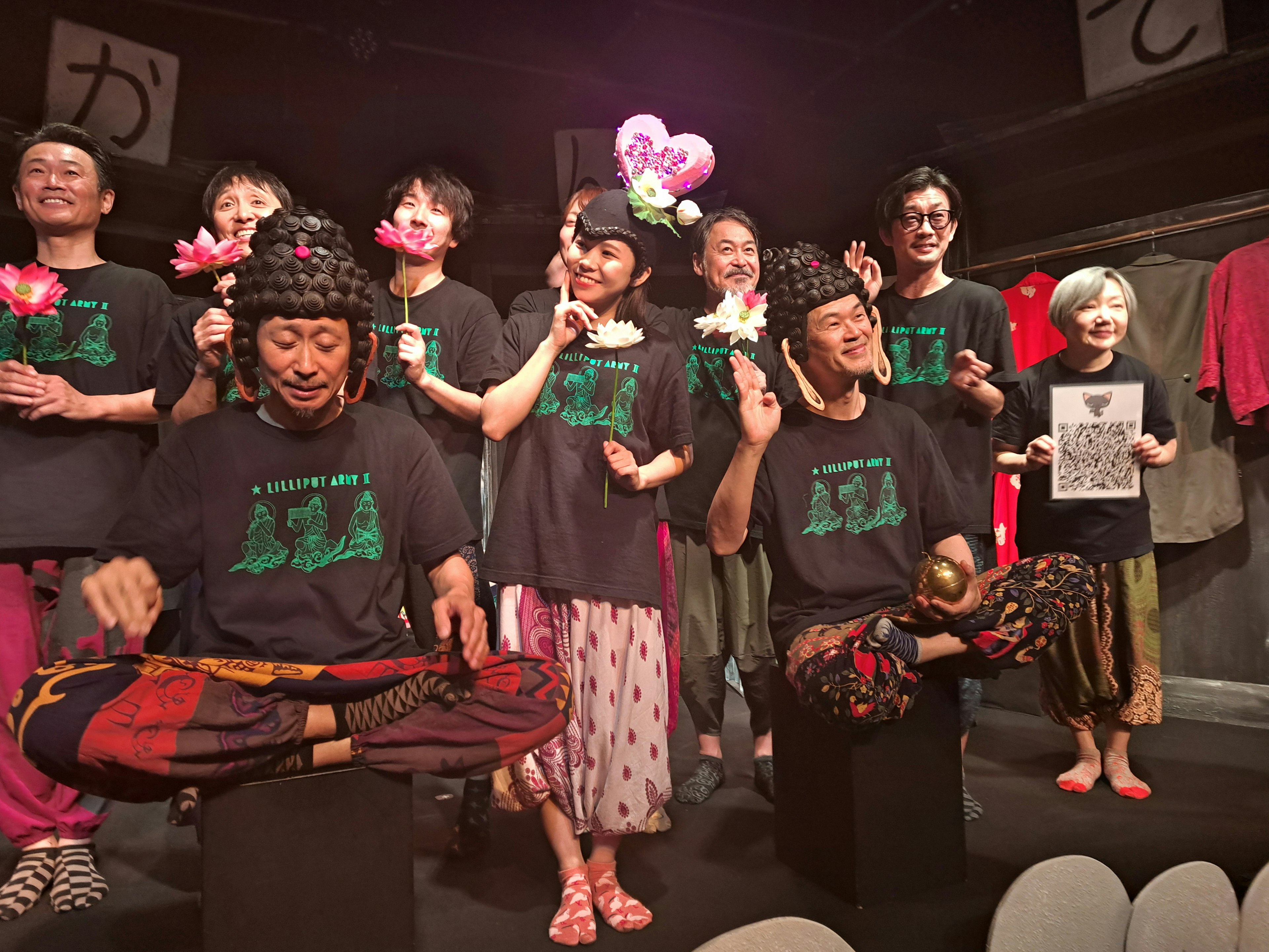 Performers posing on stage holding flowers and balloons