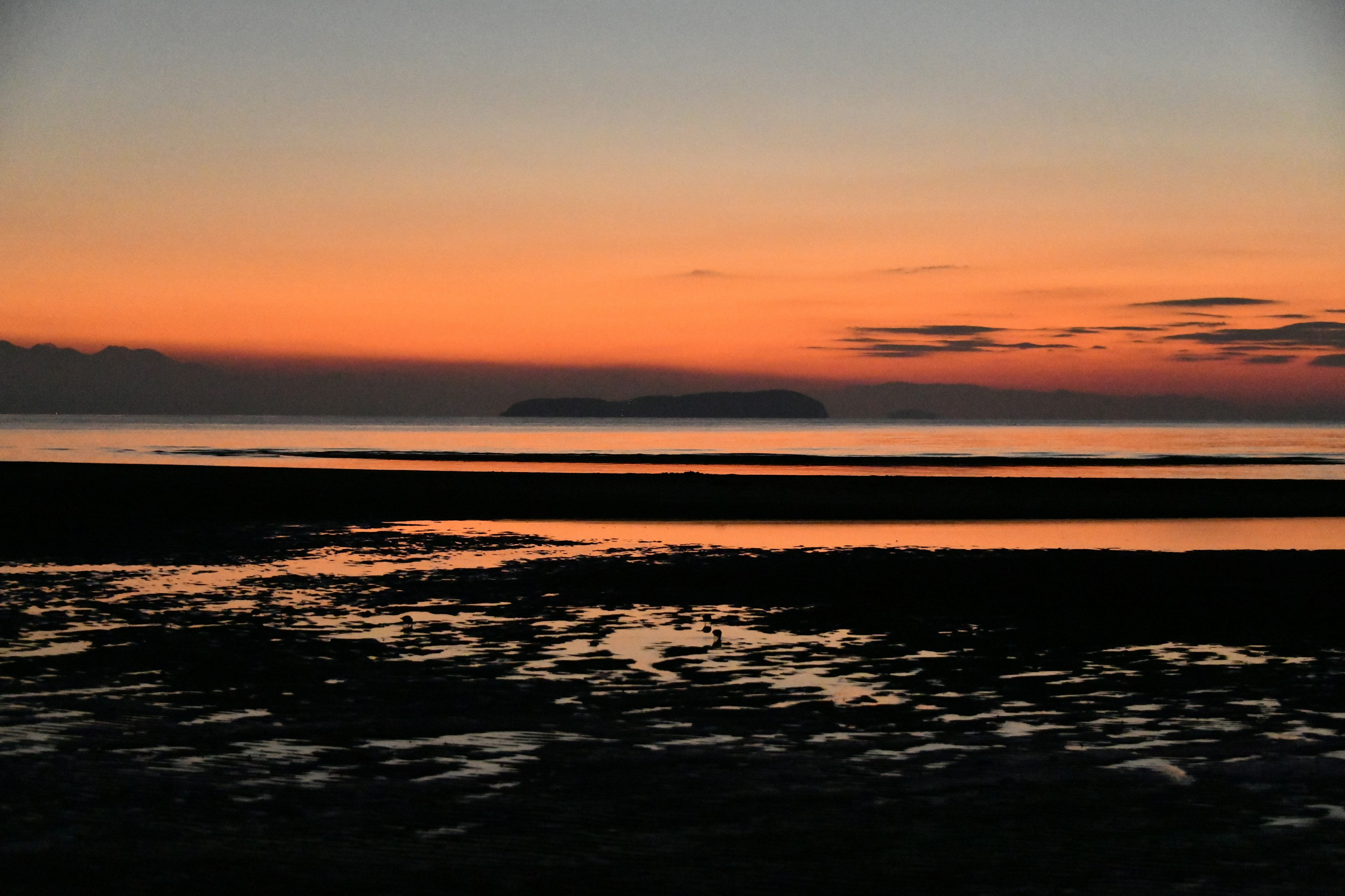 Magnifique coucher de soleil sur la mer calme et une île lointaine