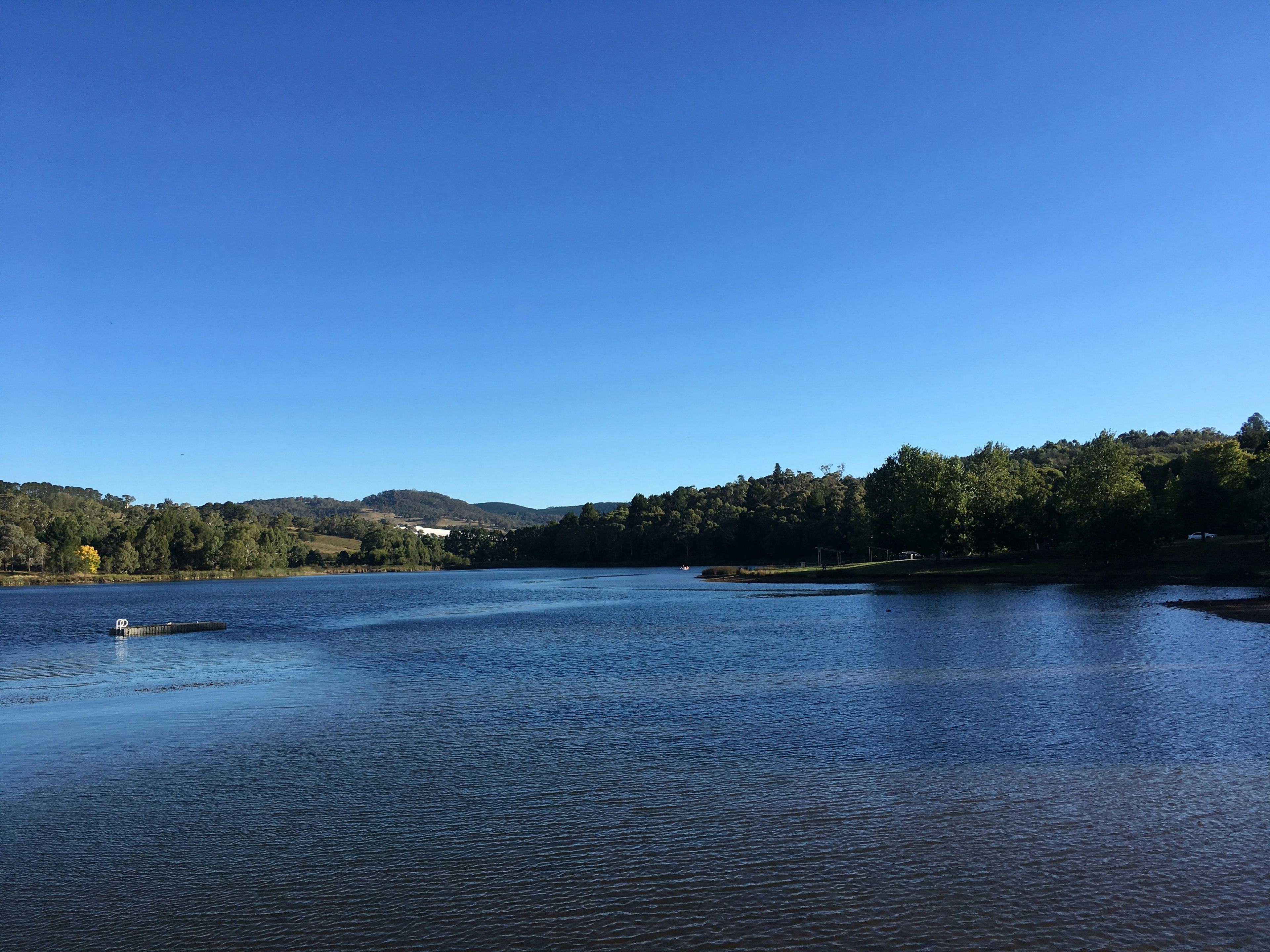 Eine ruhige Seeszene mit klarem blauen Himmel und ruhigem Wasser