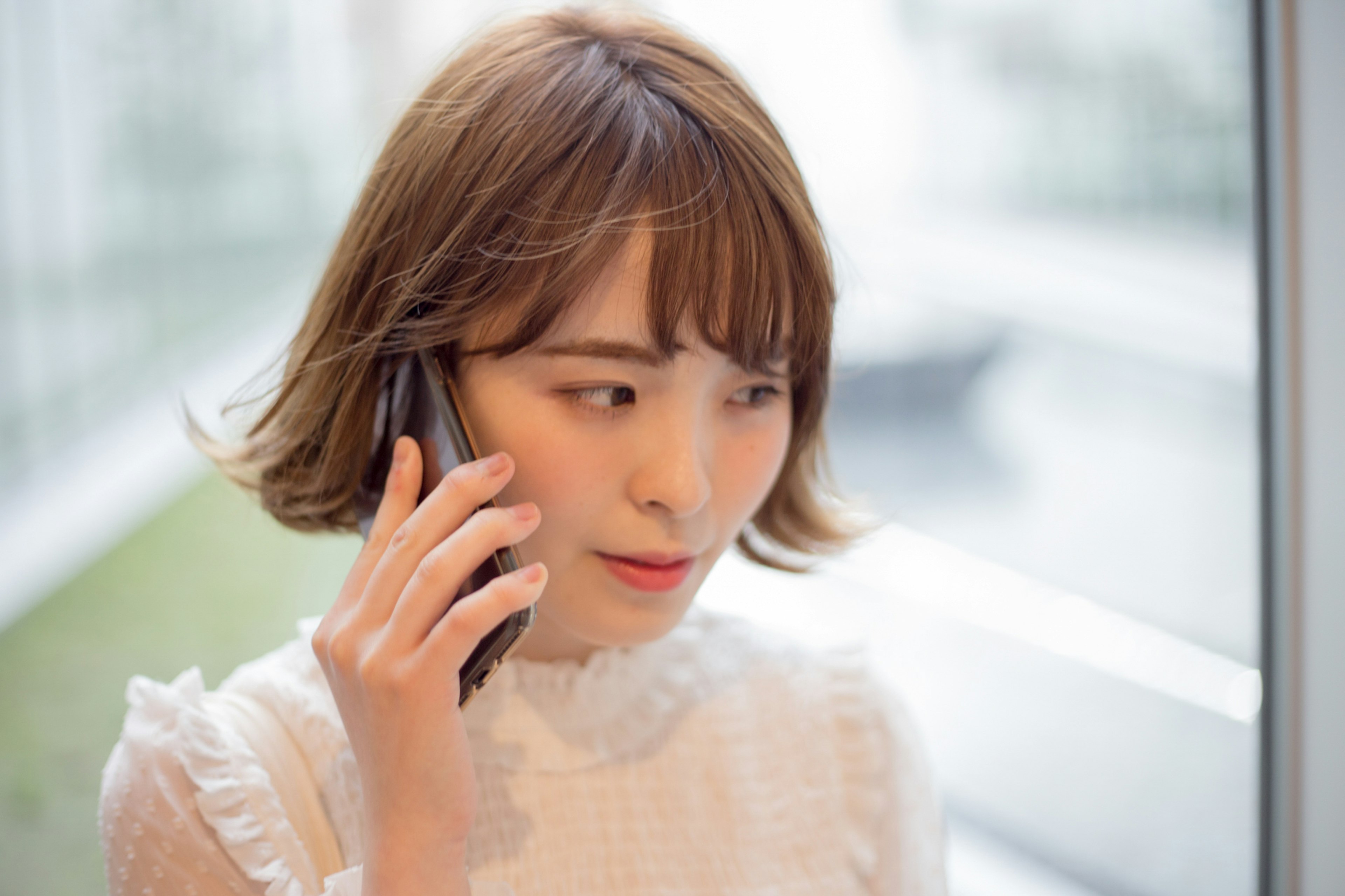 Porträt einer Frau, die am Telefon spricht, nahe einem Fenster