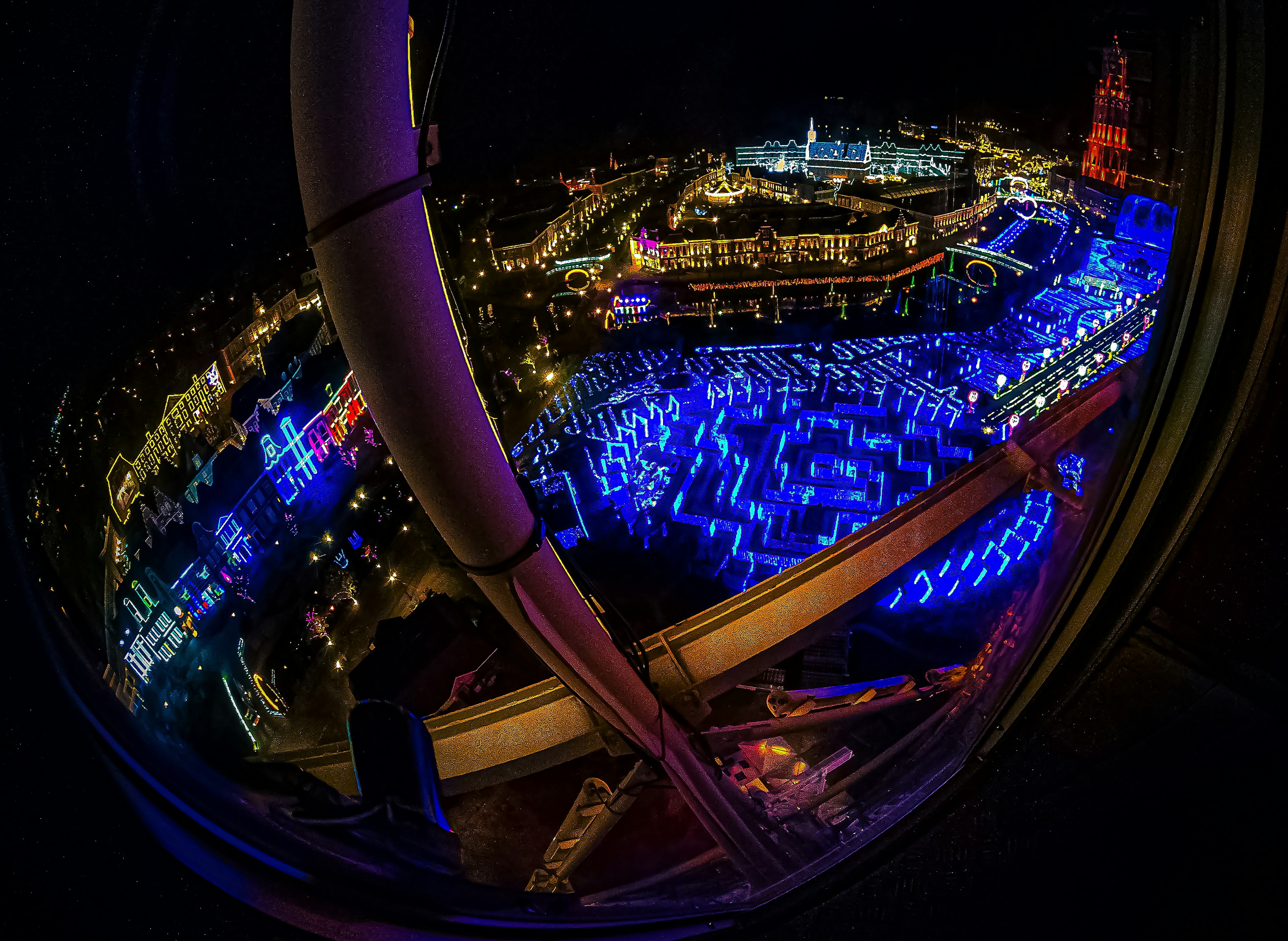 View from a Ferris wheel at night showcasing colorful lights in an amusement park