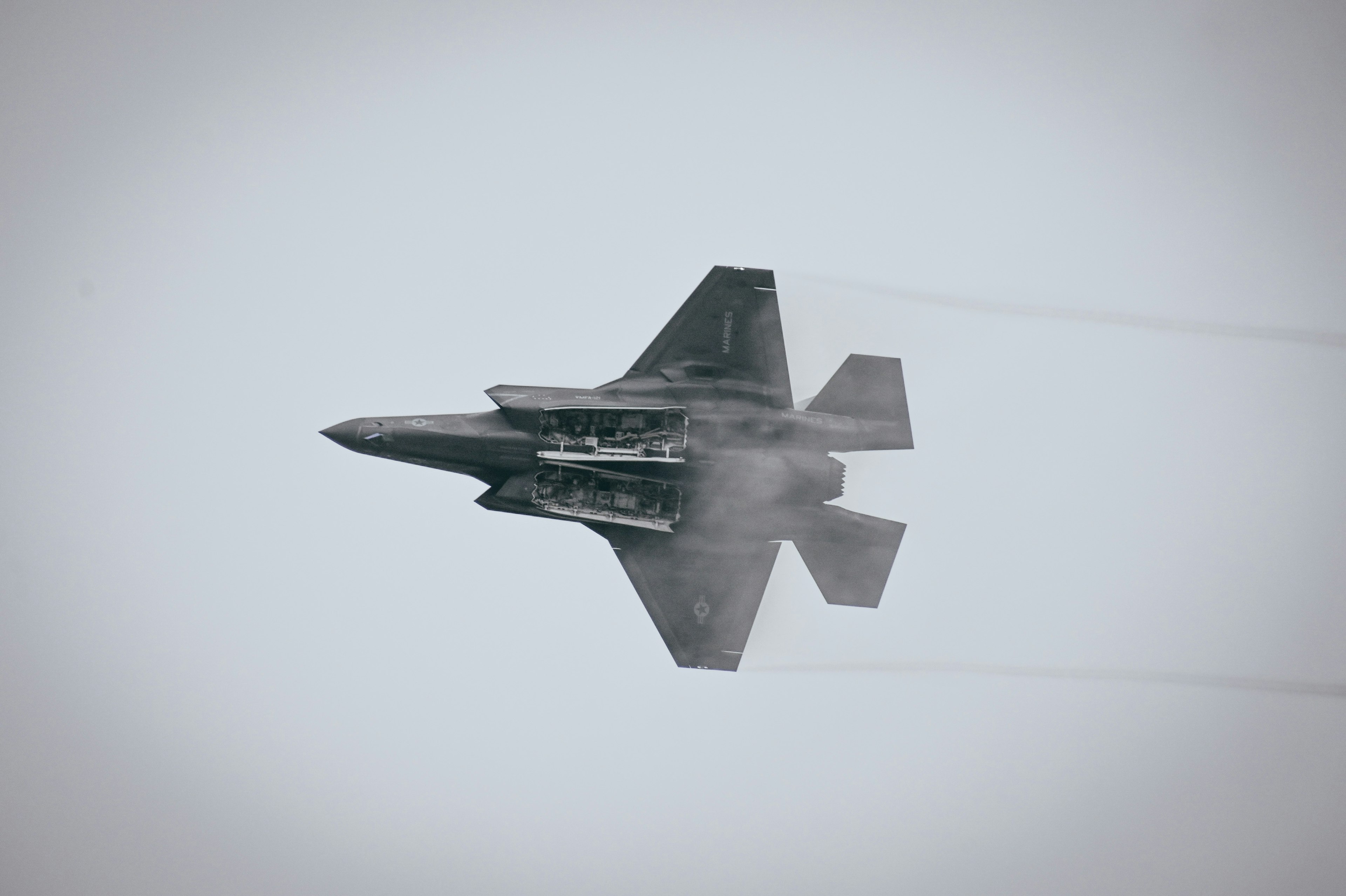 F-35 fighter jet flying through the sky leaving vapor trails