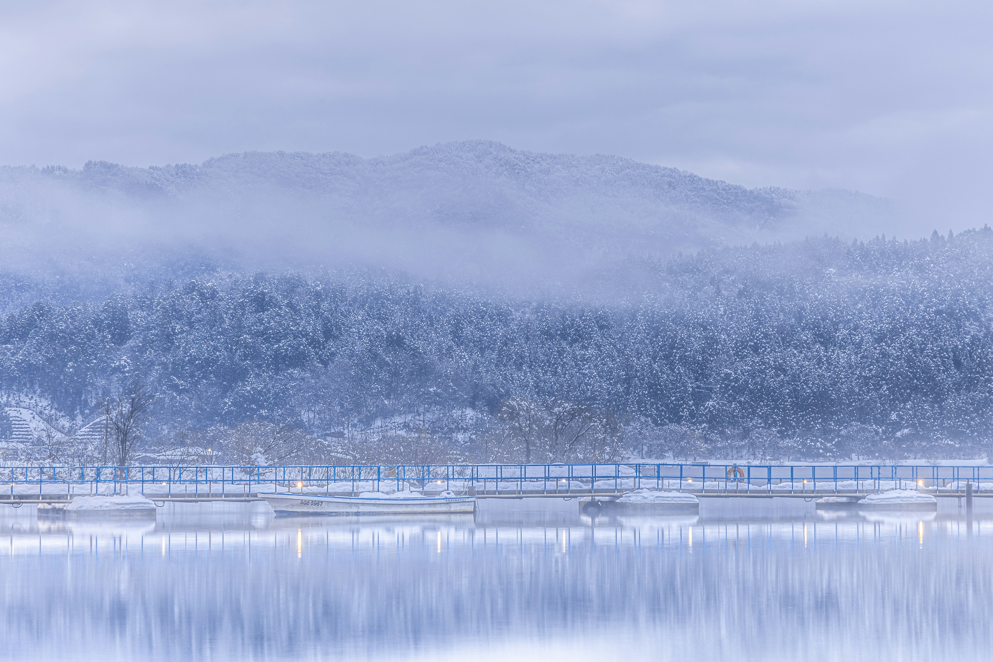 雾气弥漫的冬季景观，雪覆盖的山脉和宁静的湖泊