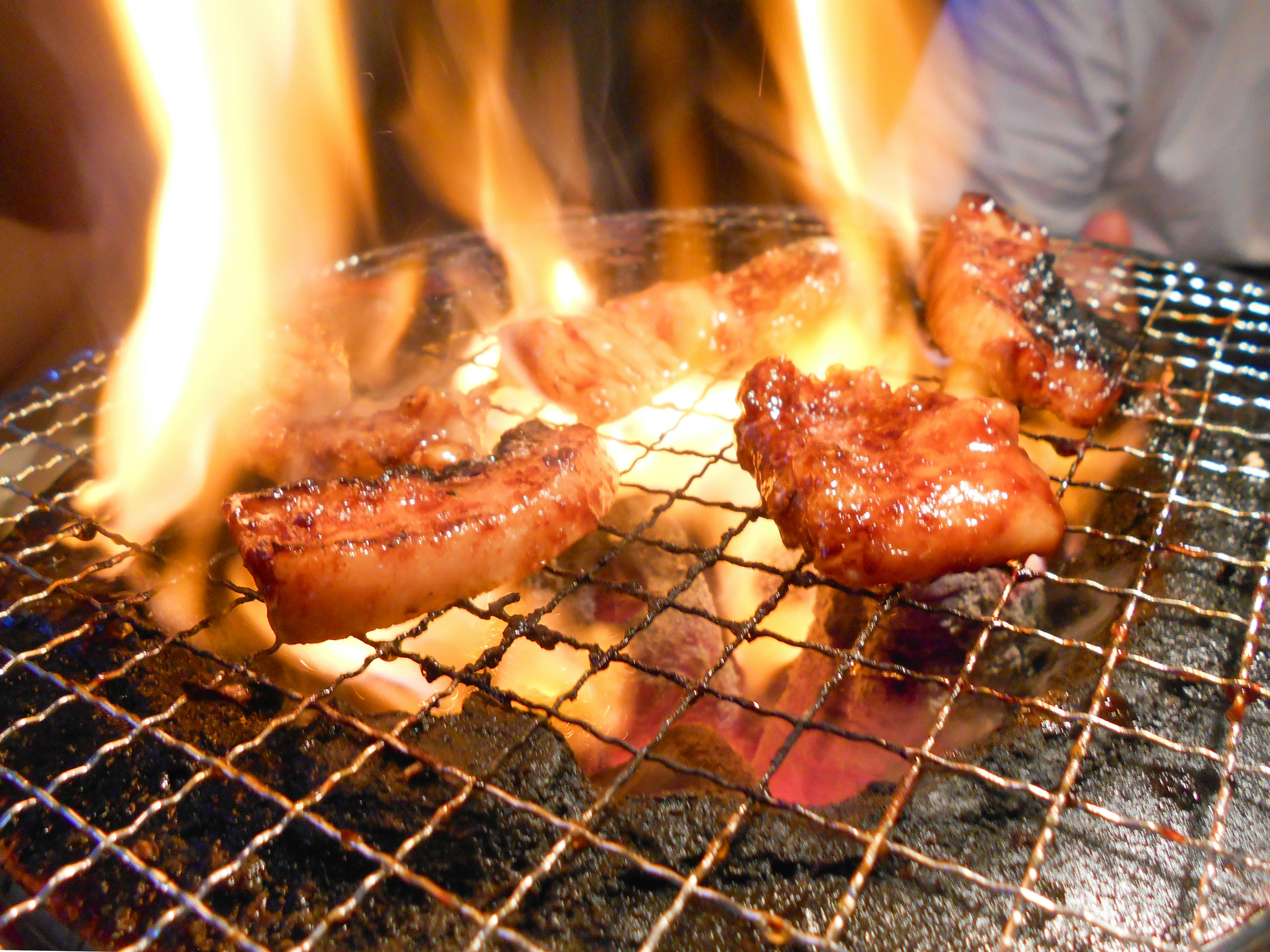 Grilled meat on a barbecue with flames