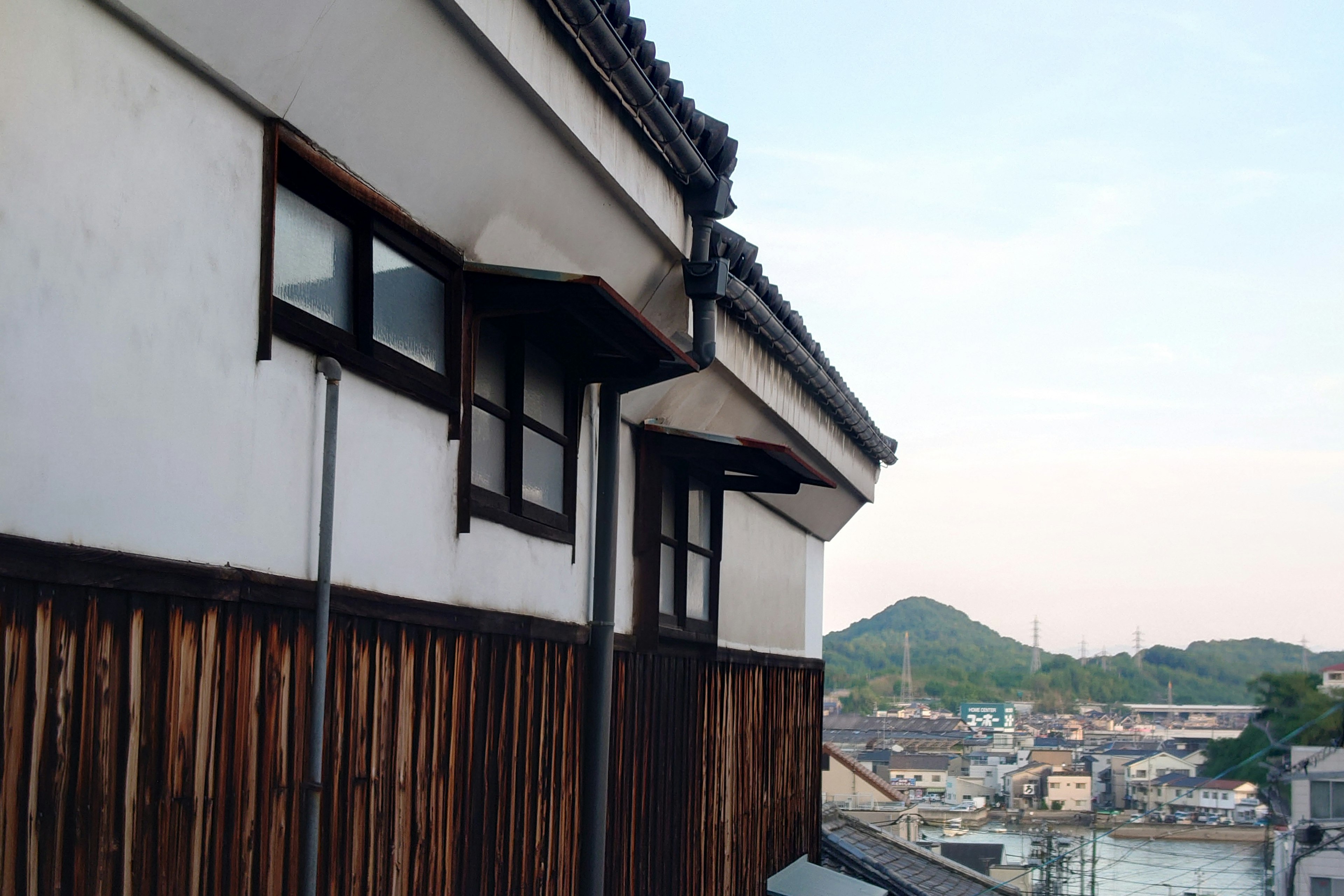 Vue latérale d'une maison japonaise traditionnelle avec un extérieur en bois et un arrière-plan de montagne