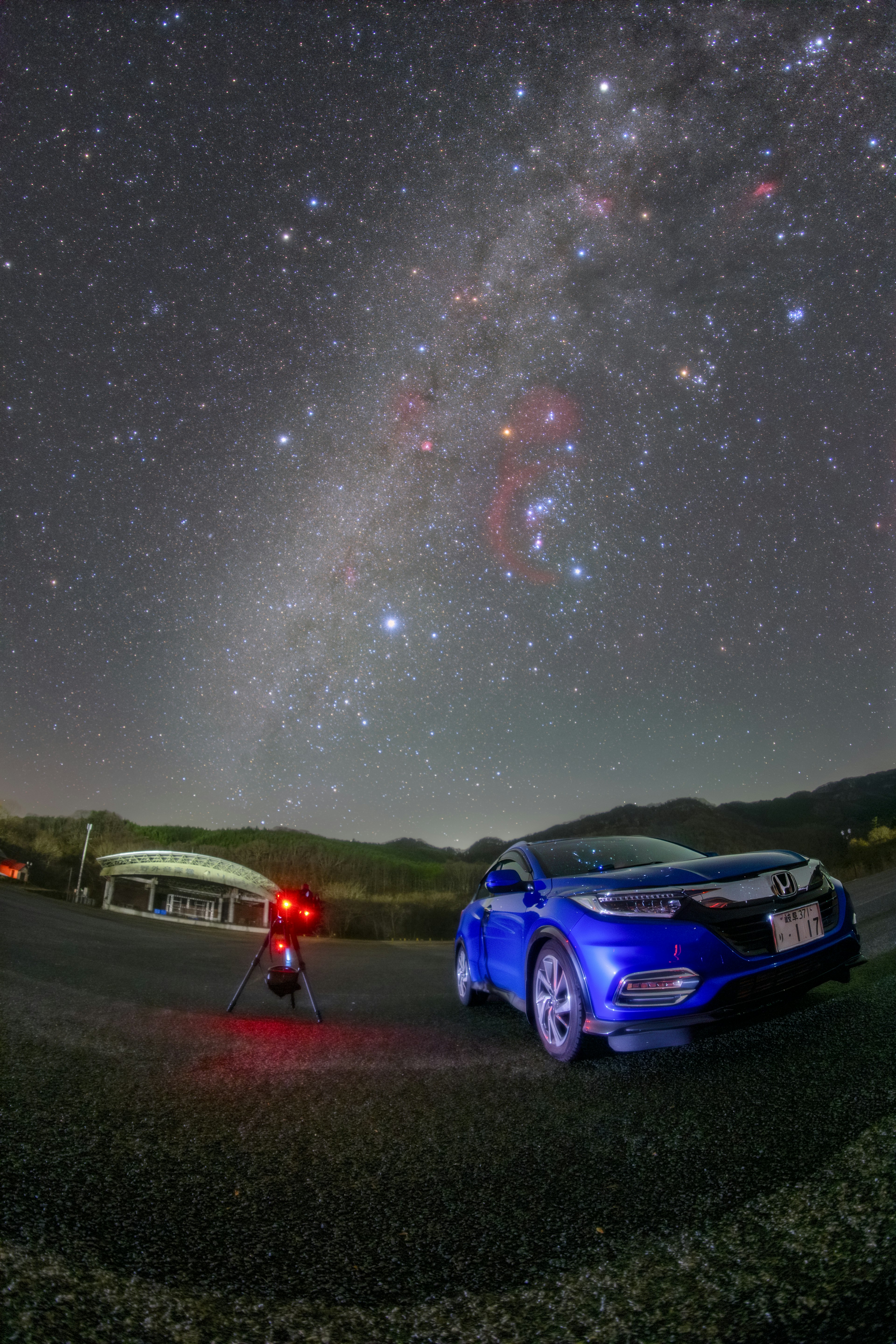 星空の下に青い車と撮影者が立っている風景