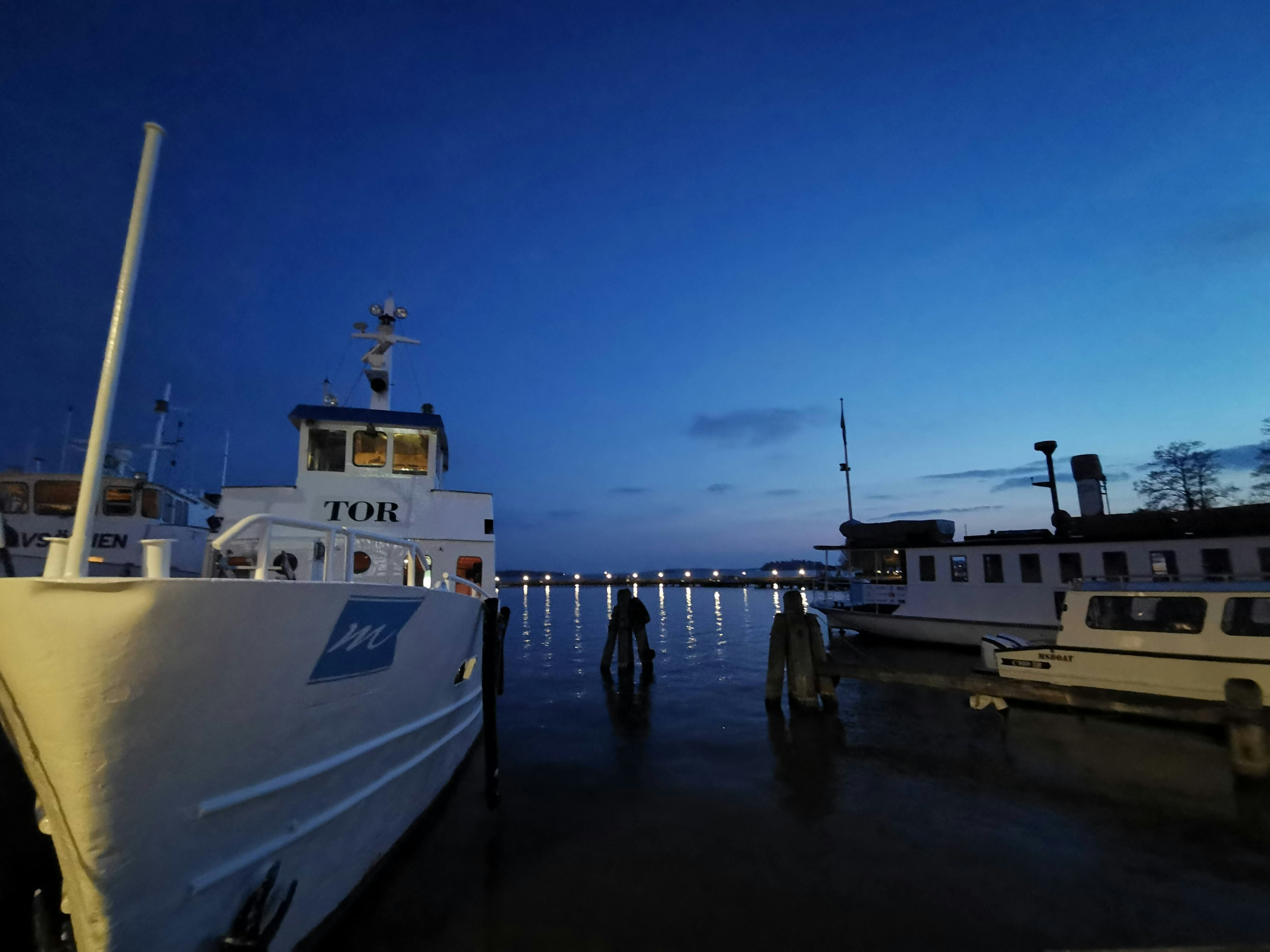 Bateaux amarrés dans un port au crépuscule avec des reflets sur l'eau