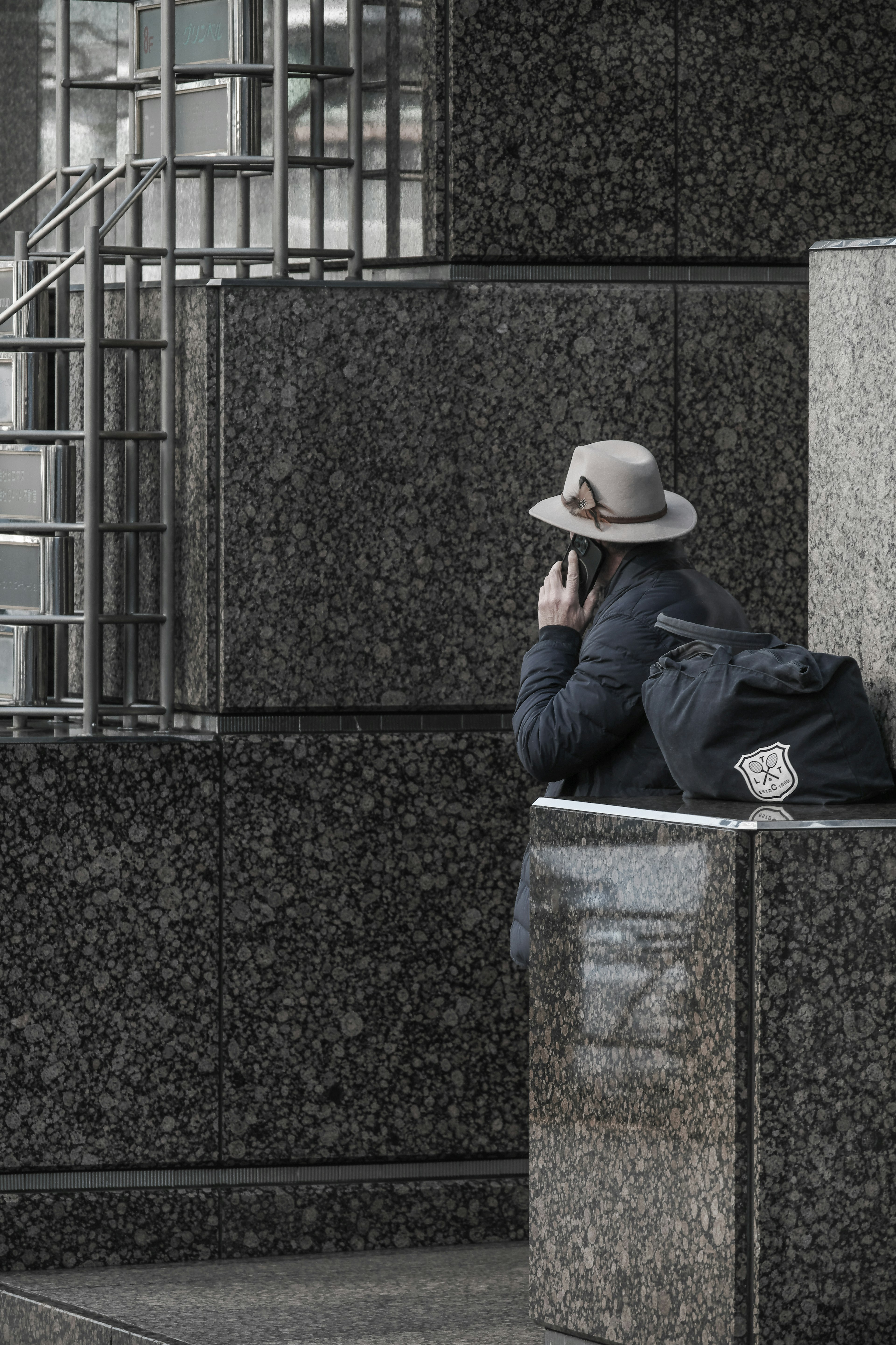 Persona con cappello che parla al telefono su sfondo grigio