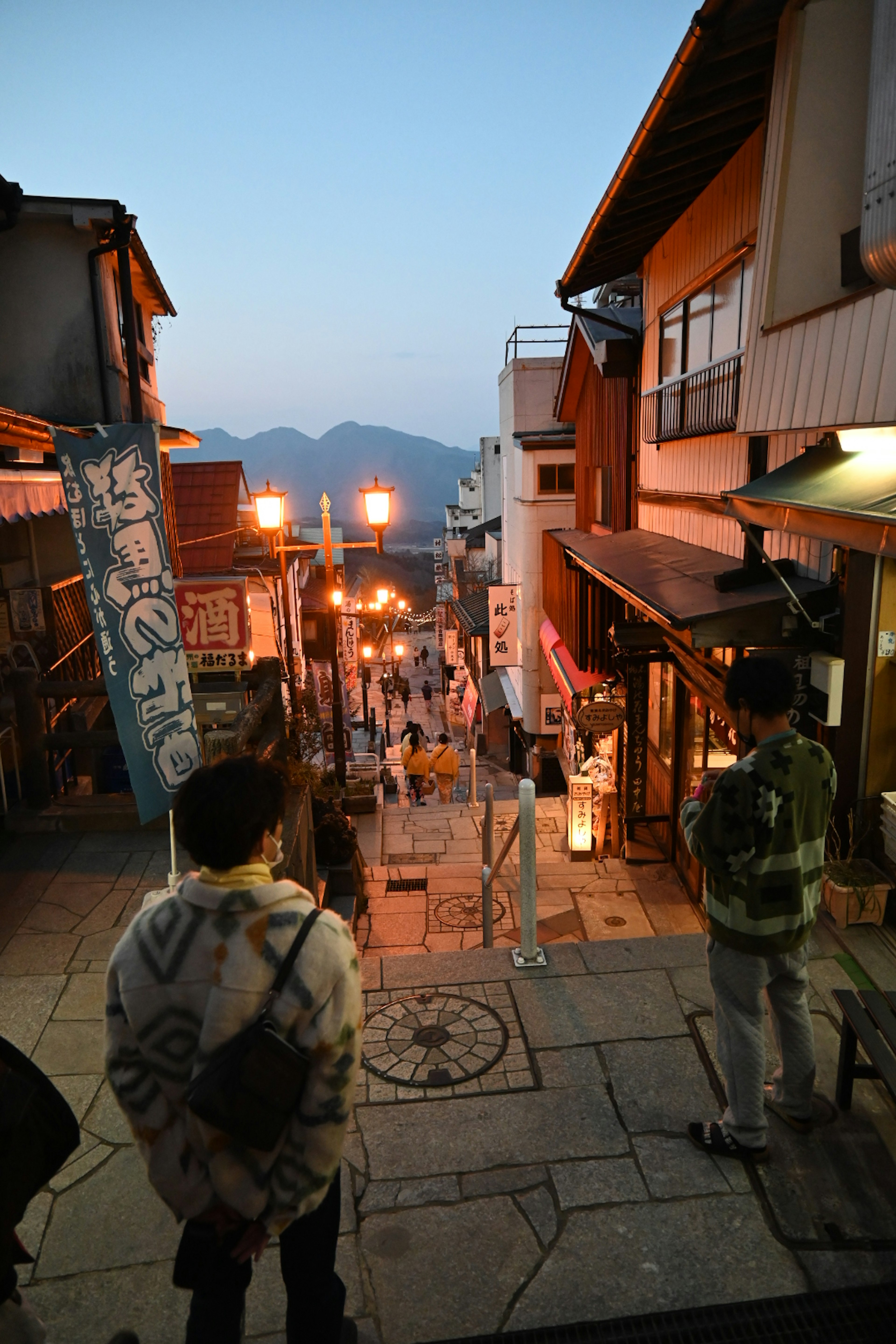 Twilight street scene with people walking and traditional buildings