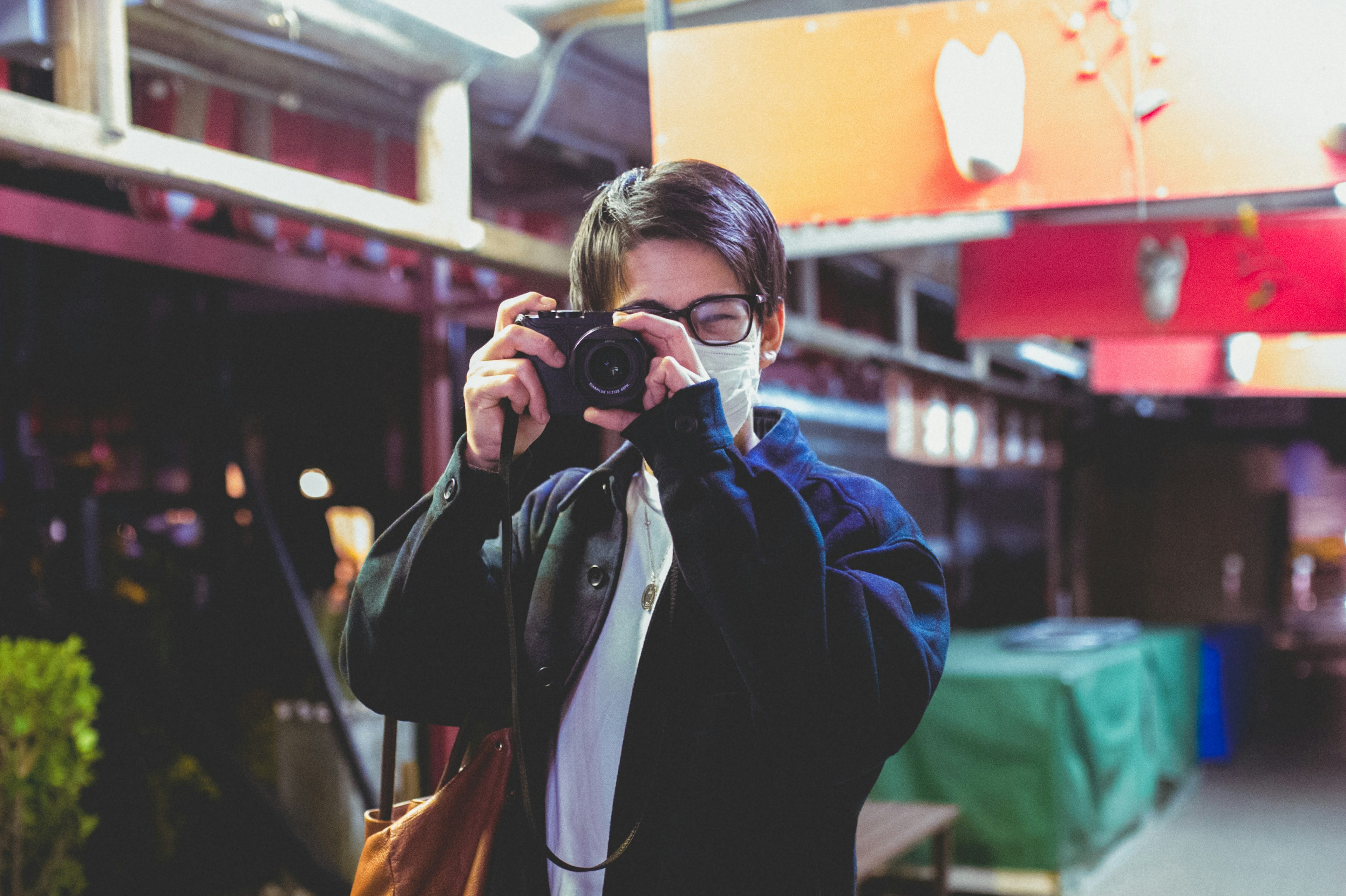 Person wearing a mask holding a camera in an outdoor night setting