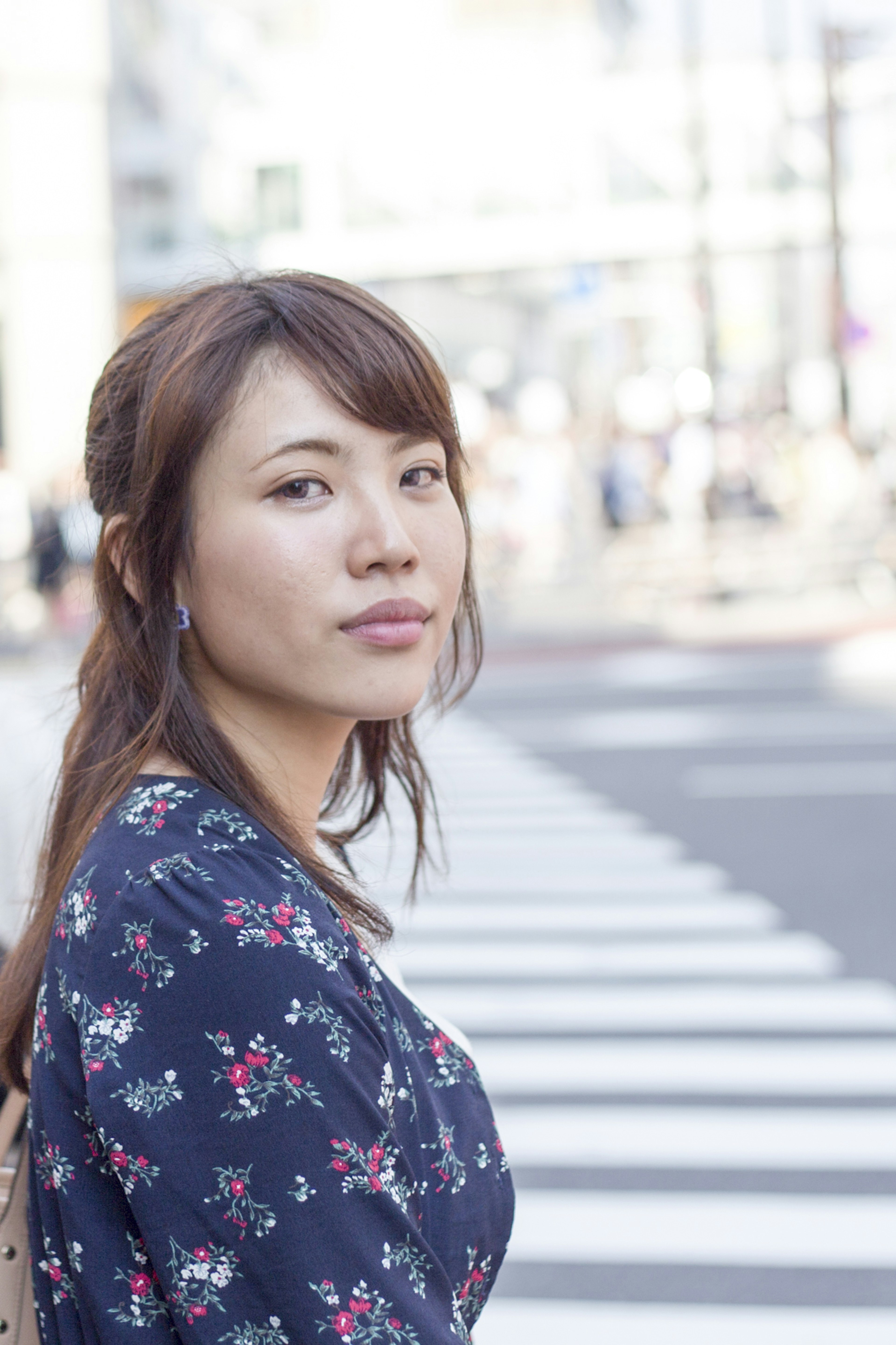 Portrait of a woman standing in front of a crosswalk wearing a floral dress