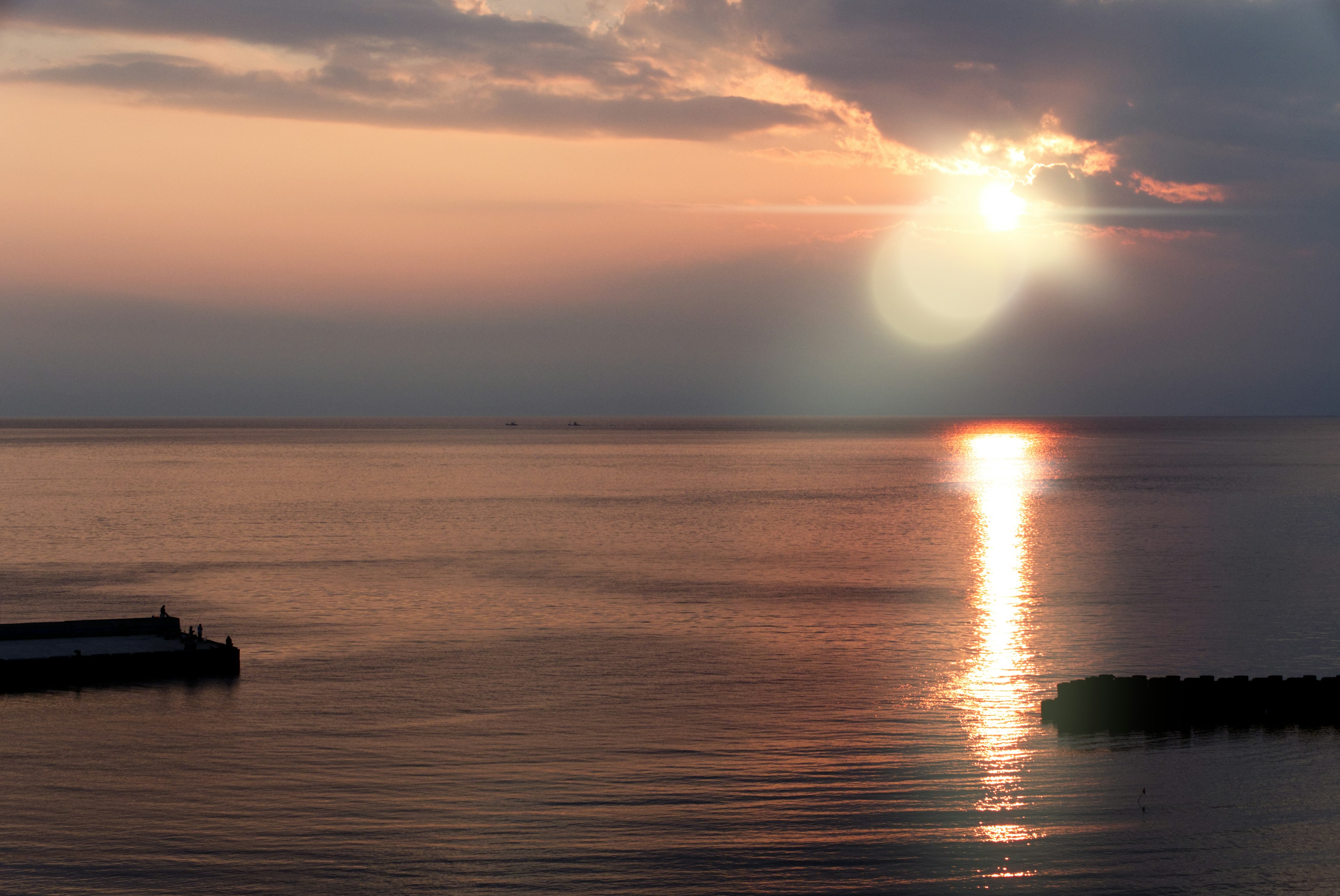 穏やかな海の上に沈む夕日と柔らかな雲