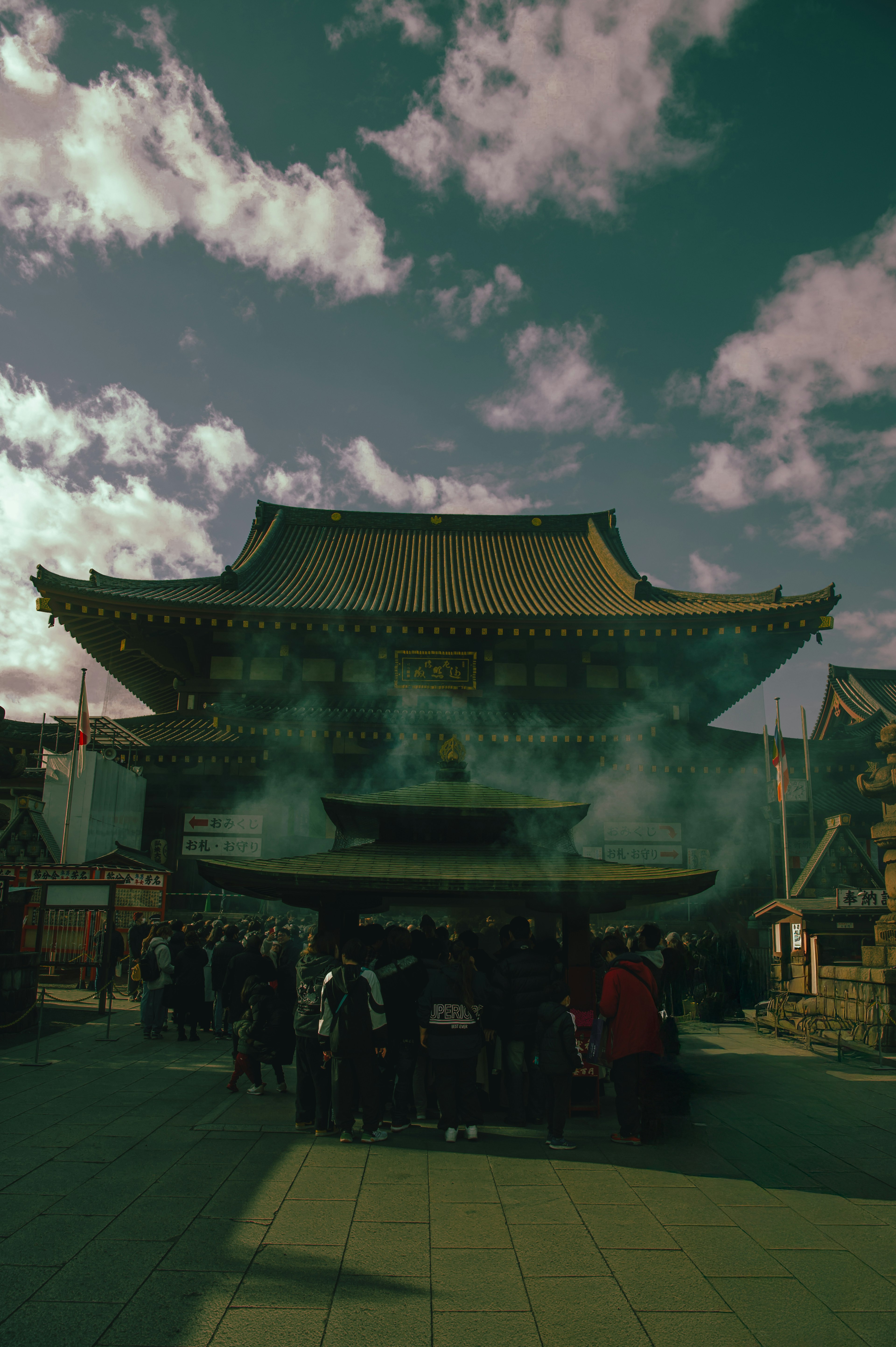 煙が立ち上る神社の前に群衆が集まる風景