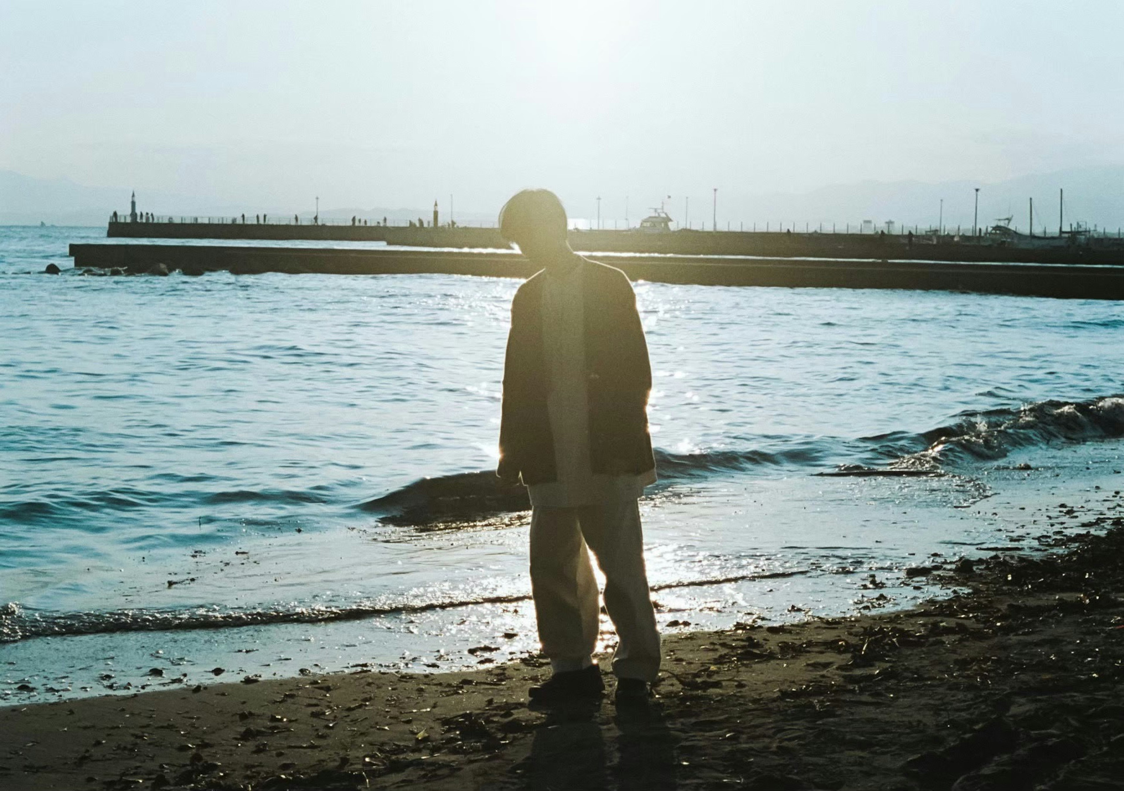 Silhouette di una persona che cammina sulla spiaggia con luce solare