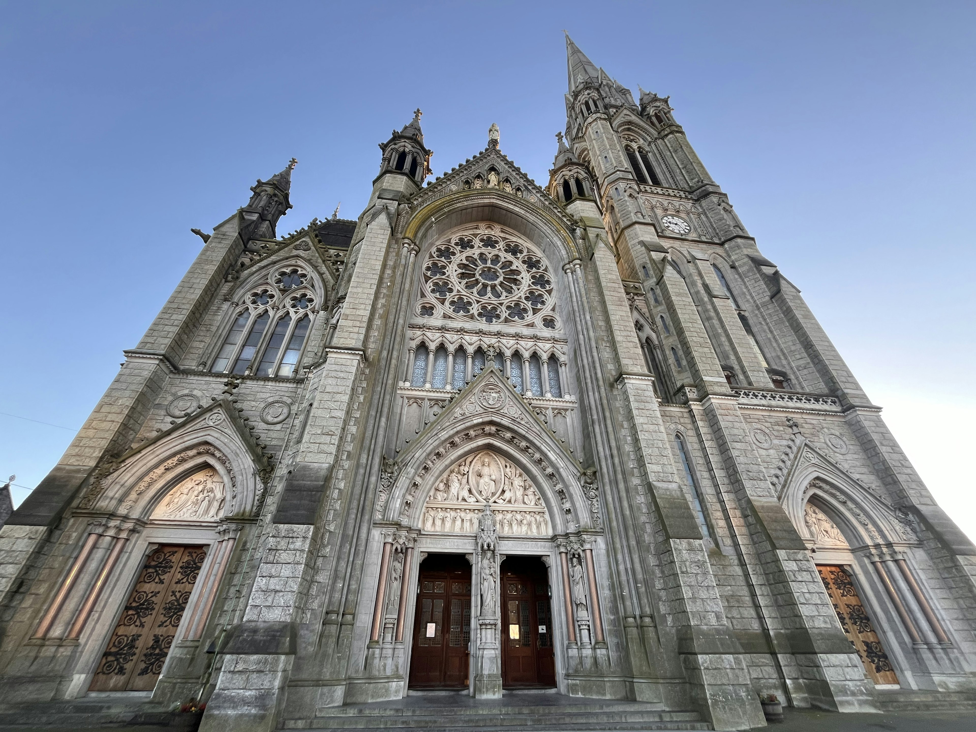 Façade majestueuse de cathédrale avec des flèches hautes détails décoratifs et une rose en pierre grise